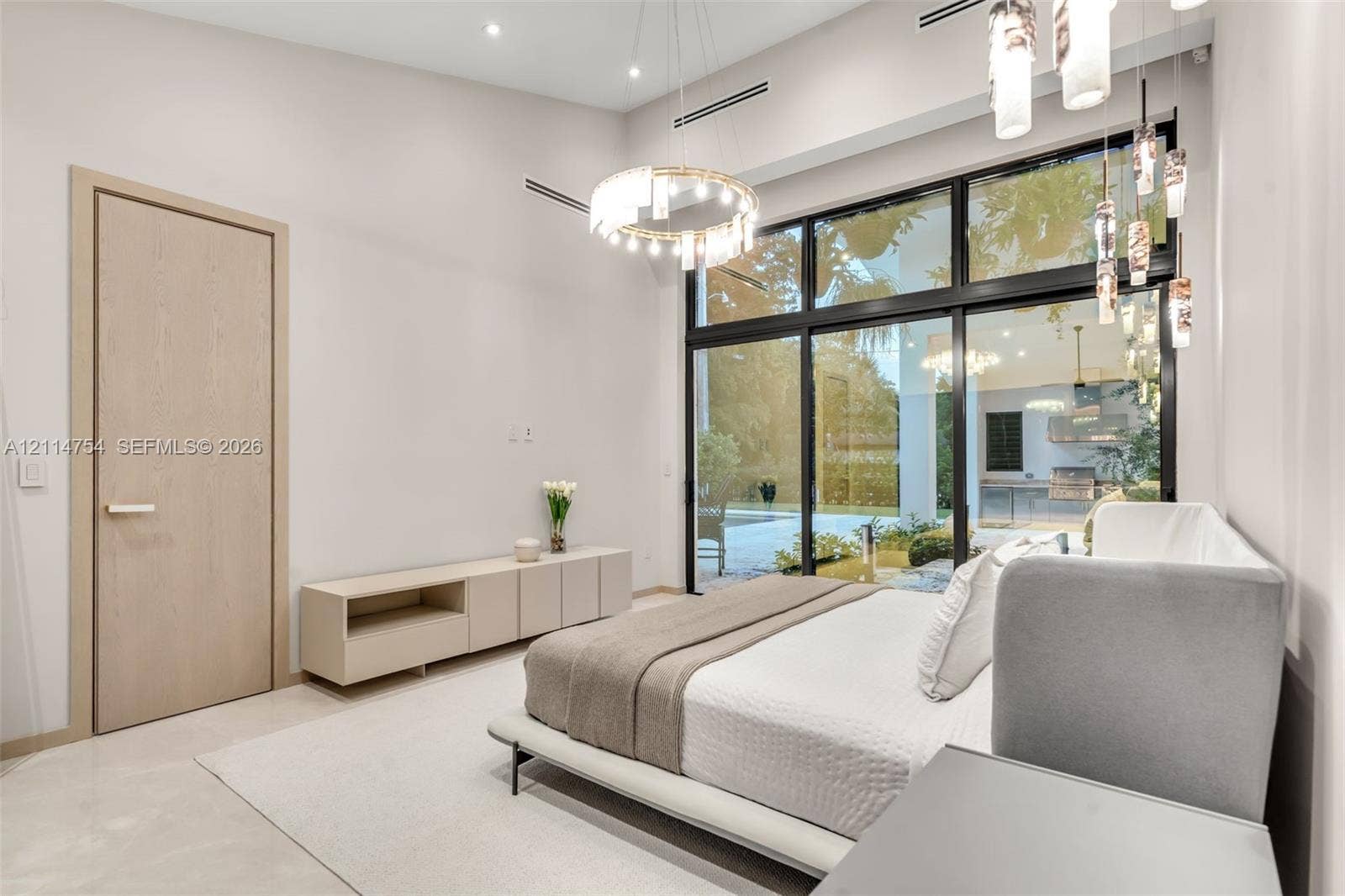 6731 SW 64th Avenue, South Miami, FL 33143 Vaulted ceilings featuring a circular crystal chandelier, recessed lighting, floor-to-ceiling black-framed windows, and built-in matte finish cabinetry