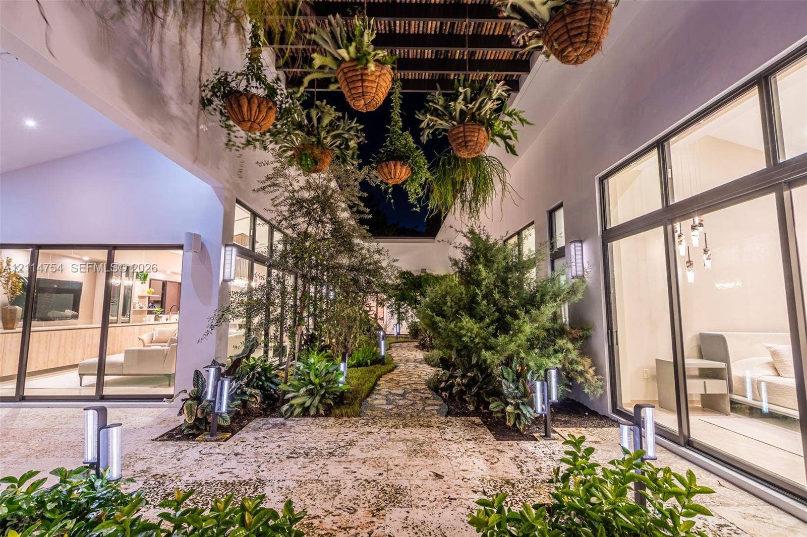 6731 SW 64th Avenue, South Miami, FL 33143 Outdoor area featuring a tiled pool and spa with built-in lighting, expansive stone-finish patio, and mature perimeter landscaping