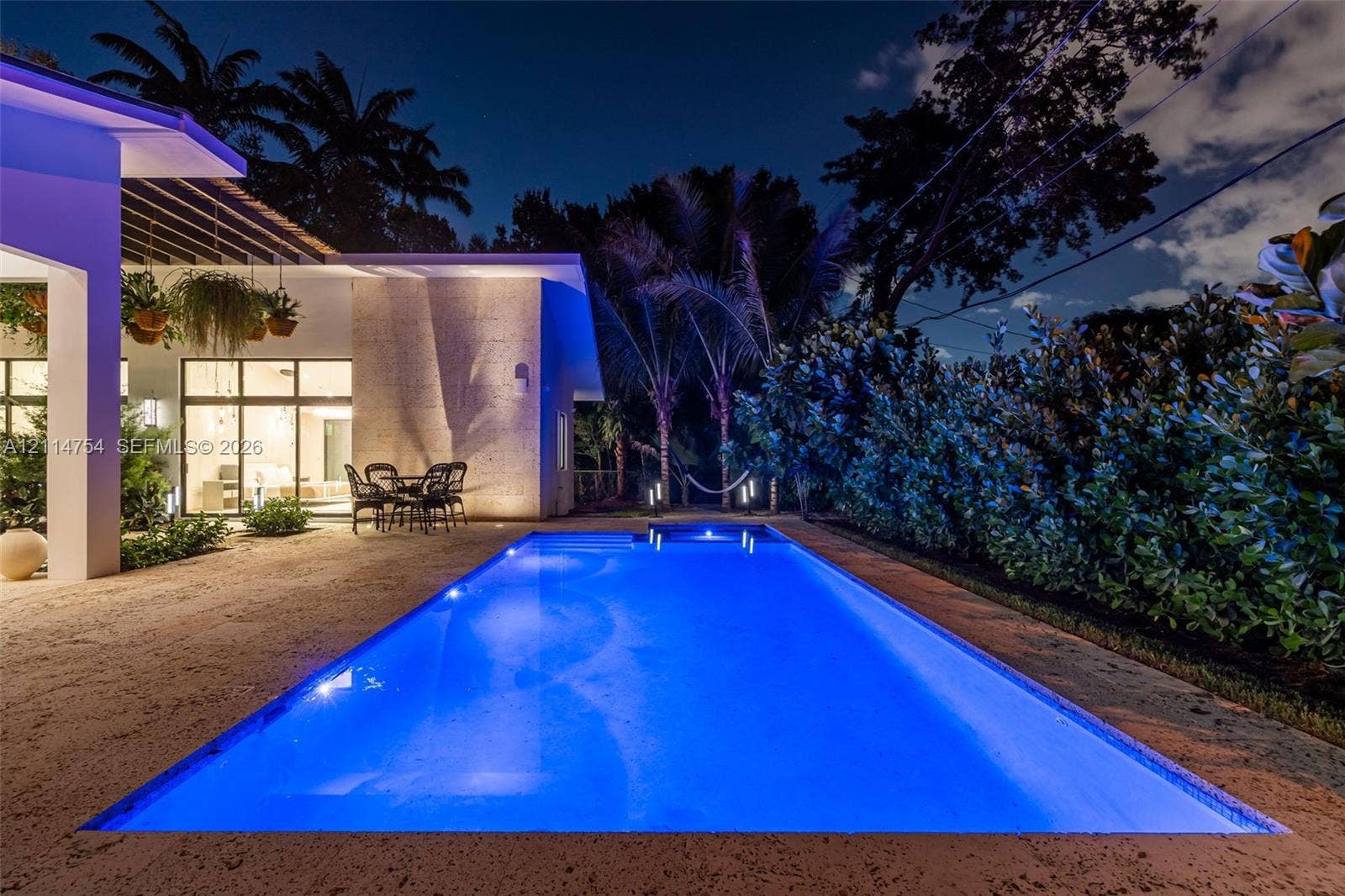 6731 SW 64th Avenue, South Miami, FL 33143 Modern exterior featuring a textured stone facade, multi-panel glass garage door, wood-finish entry door, and stone paver walkway