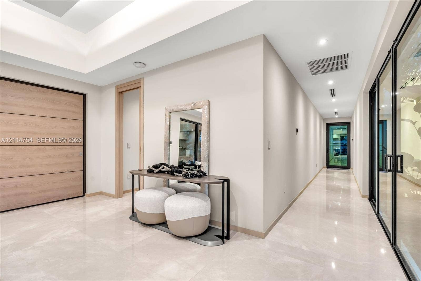 6731 SW 64th Avenue, South Miami, FL 33143 Modern kitchen featuring a waterfall-edge island, stone-surfaced countertops, custom wood-finish cabinetry, floor-to-ceiling black-framed windows, and a multi-pendant light fixture