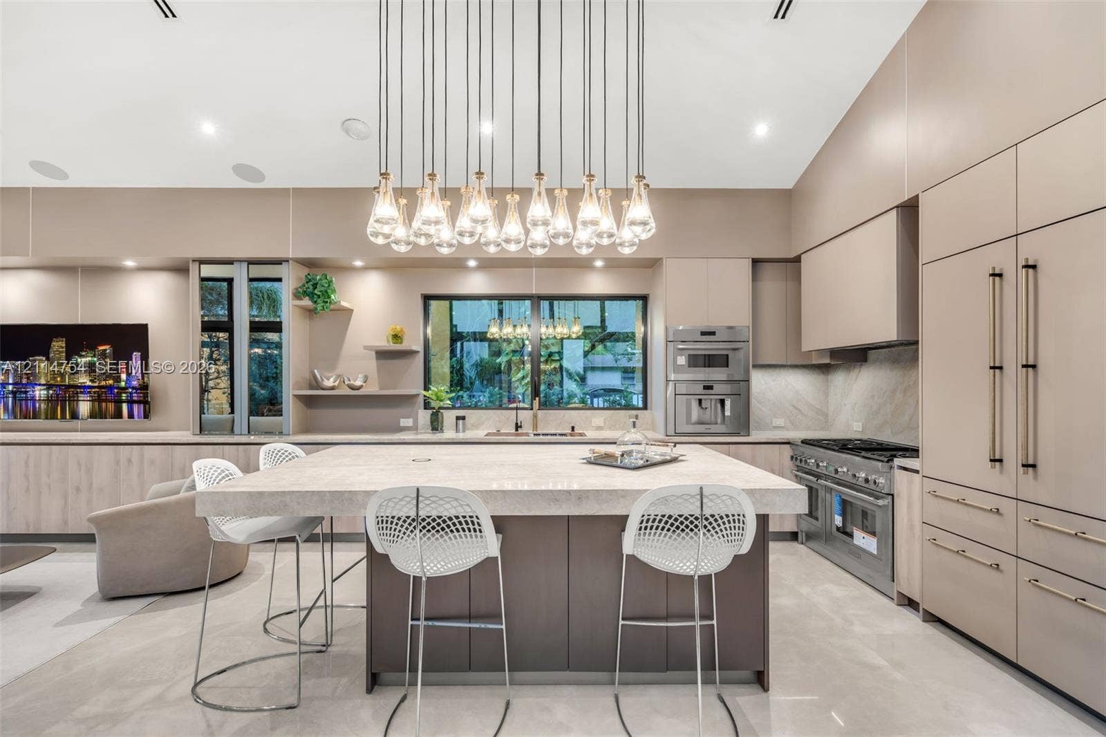 6731 SW 64th Avenue, South Miami, FL 33143 Vaulted ceilings, extensive custom cabinetry with light wood-finish detailing, recessed lighting, multi-light linear pendant fixture, and large-format tile flooring