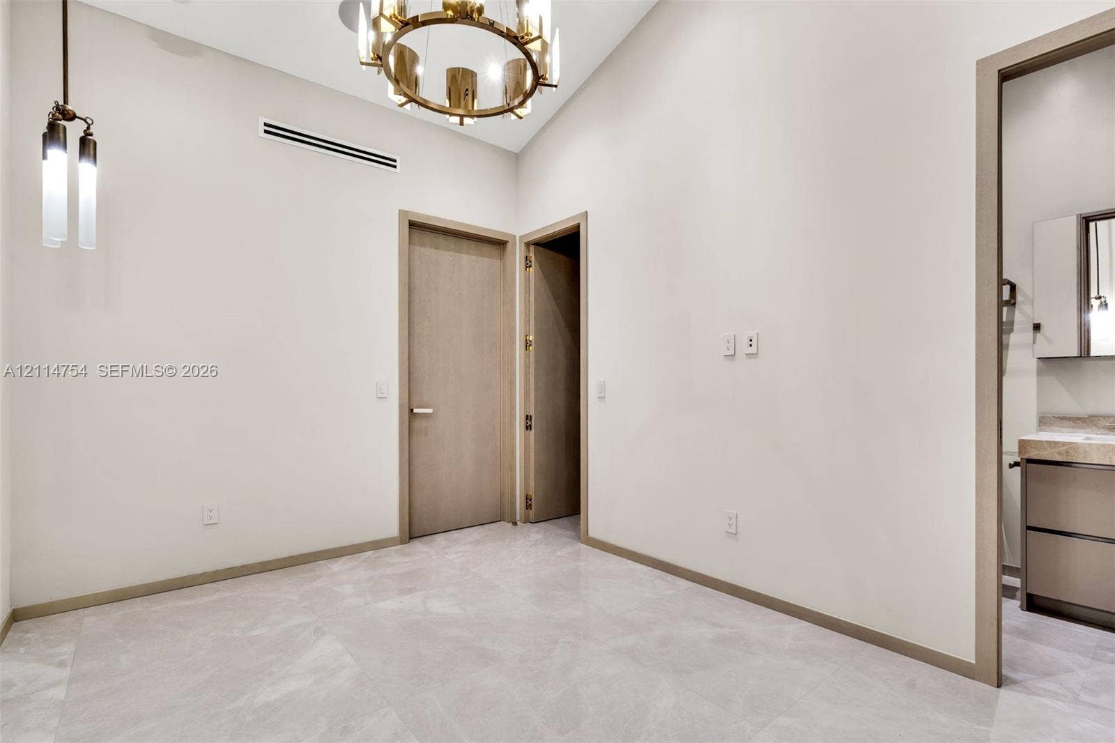 6731 SW 64th Avenue, South Miami, FL 33143 Interior space featuring high ceilings, polished stone-finish flooring, a multi-pane sliding glass door, a tiered metal chandelier, and a pendant light fixture
