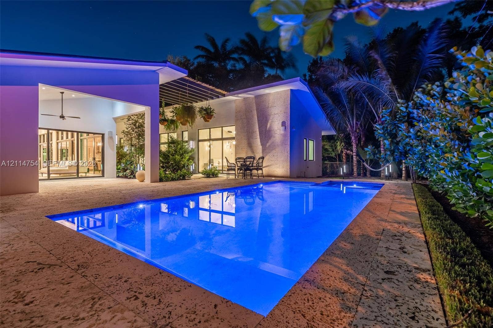 6731 SW 64th Avenue, South Miami, FL 33143 Outdoor kitchen featuring stainless steel cabinetry, integrated grill, and a professional-grade range hood, complemented by stone flooring and an in-ground swimming pool