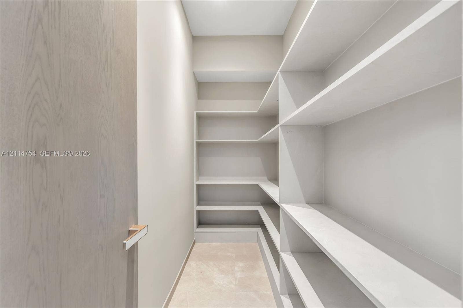6731 SW 64th Avenue, South Miami, FL 33143 Vaulted ceilings, large-scale crystal chandelier, built-in cabinetry with light wood finish, stone-finish flooring, and floor-to-ceiling glass wall panels