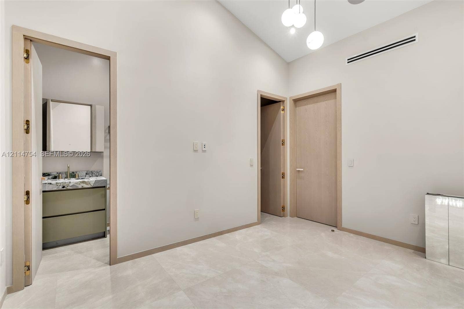 6731 SW 64th Avenue, South Miami, FL 33143 High ceilings featuring tiered globe pendant lighting, oversized sliding glass doors with dark frames, and polished neutral-toned tile flooring