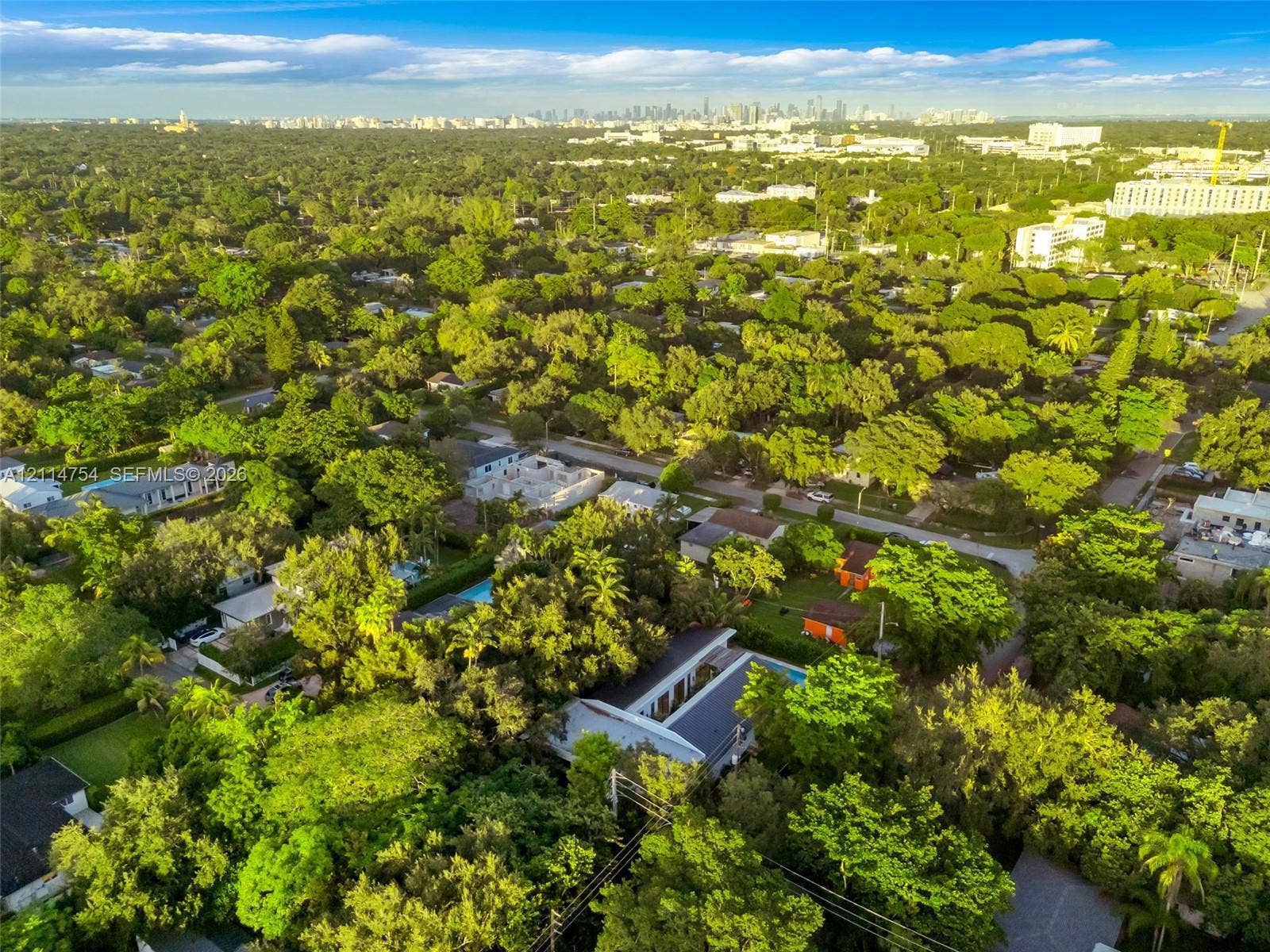 6731 SW 64th Avenue, South Miami, FL 33143 Aerial perspective of a detached residential property featuring a flat roofline, central skylight structure, and a backyard swimming pool, set within a heavily wooded lot
