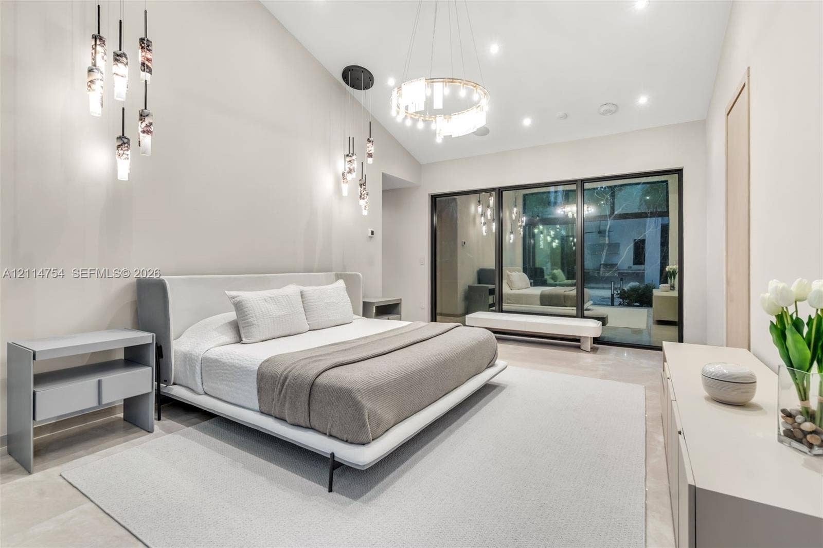 6731 SW 64th Avenue, South Miami, FL 33143 Stone-tiled walls and flooring paired with a freestanding soaking tub, brass fixtures, glass-enclosed walk-in shower, and dual vanities with integrated shelving