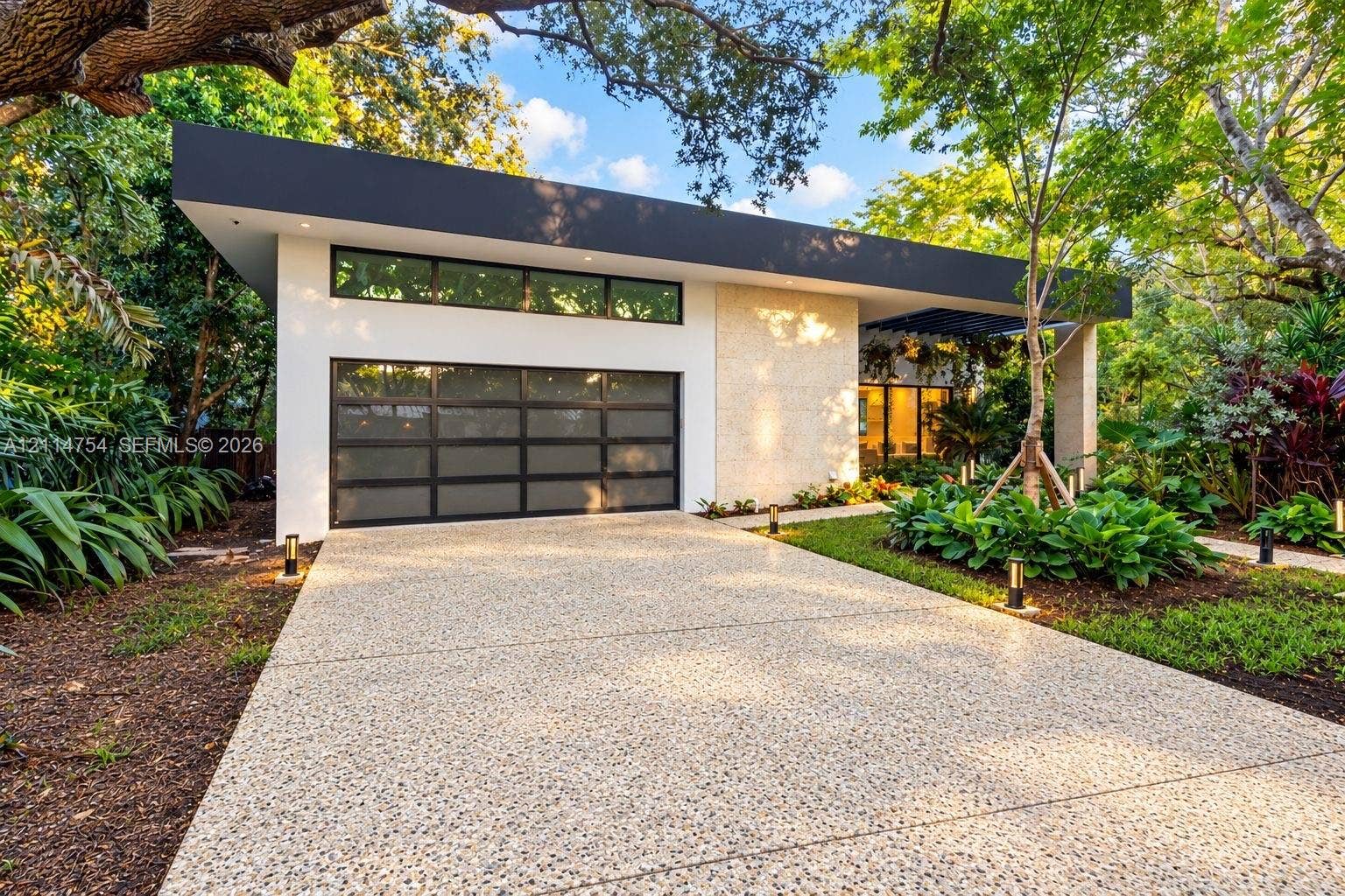 6731 SW 64th Avenue, South Miami, FL 33143 Expansive open-concept living area featuring a recessed tray ceiling with integrated cove lighting, polished stone flooring, custom built-in cabinetry with floating shelving, and floor-to-ceiling glass panel doors