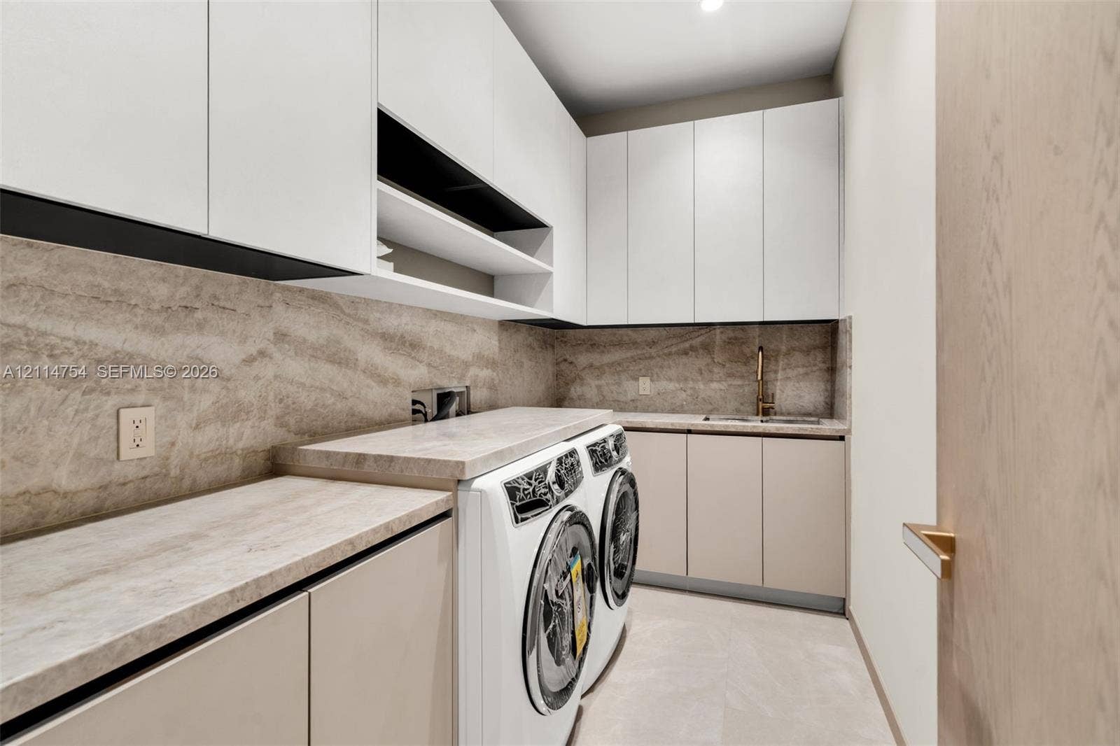 6731 SW 64th Avenue, South Miami, FL 33143 Bathroom featuring a glass-enclosed shower with a rainfall showerhead, stone-finish vanity countertop with an integrated basin, brushed gold-tone fixtures, and a mirrored medicine cabinet