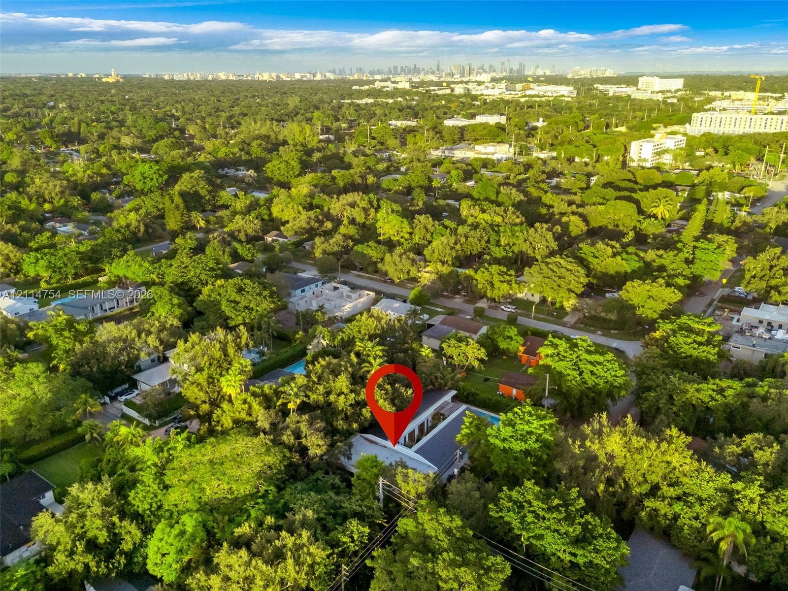 6731 SW 64th Avenue, South Miami, FL 33143 Aerial perspective of property featuring dense mature tree canopy, integrated paved central courtyard, and dark-toned metal roofing