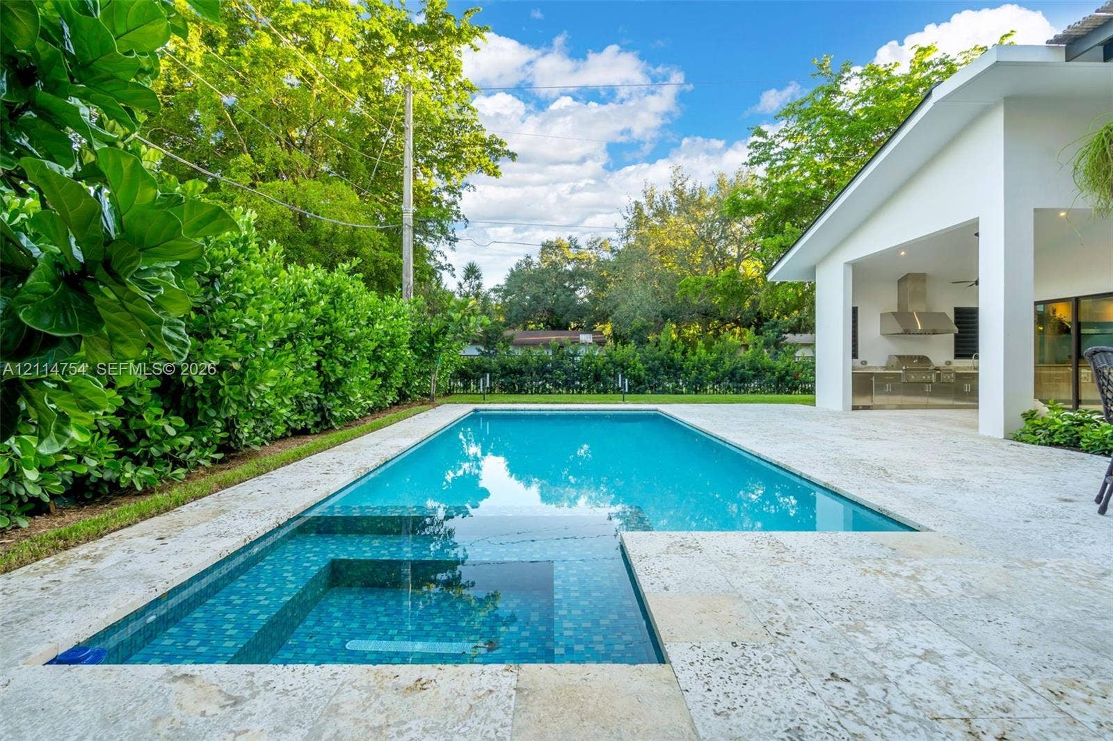 6731 SW 64th Avenue, South Miami, FL 33143 Swimming pool with stone-tiled decking, covered patio with integrated ceiling fan, and exterior wall cladding
