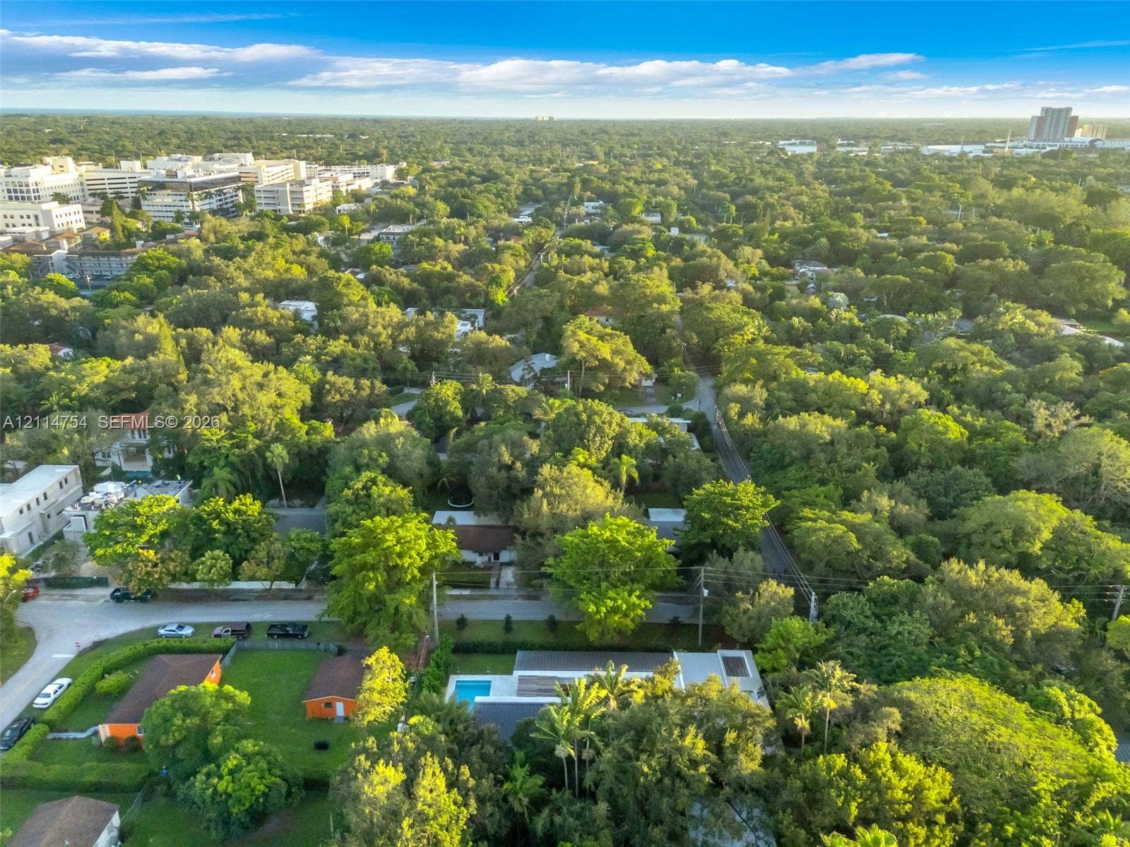 6731 SW 64th Avenue, South Miami, FL 33143 Aerial perspective of a contemporary residence featuring a flat roofline, a private rectangular pool, and extensive mature landscaping