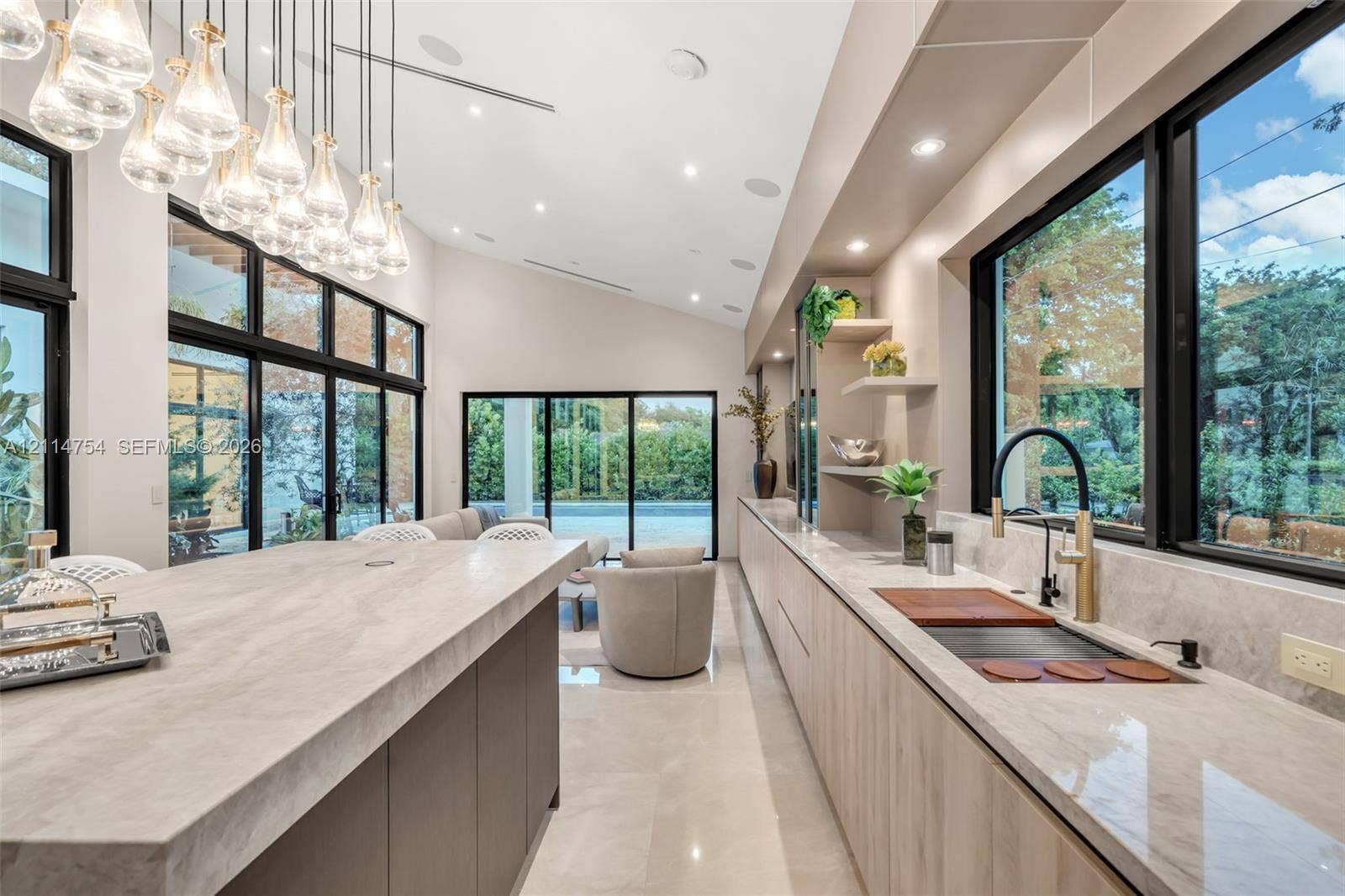 6731 SW 64th Avenue, South Miami, FL 33143 Vaulted ceilings with recessed lighting, floor-to-ceiling multi-panel glass doors, custom wall-to-wall cabinetry with stone countertops, and integrated ceiling speakers
