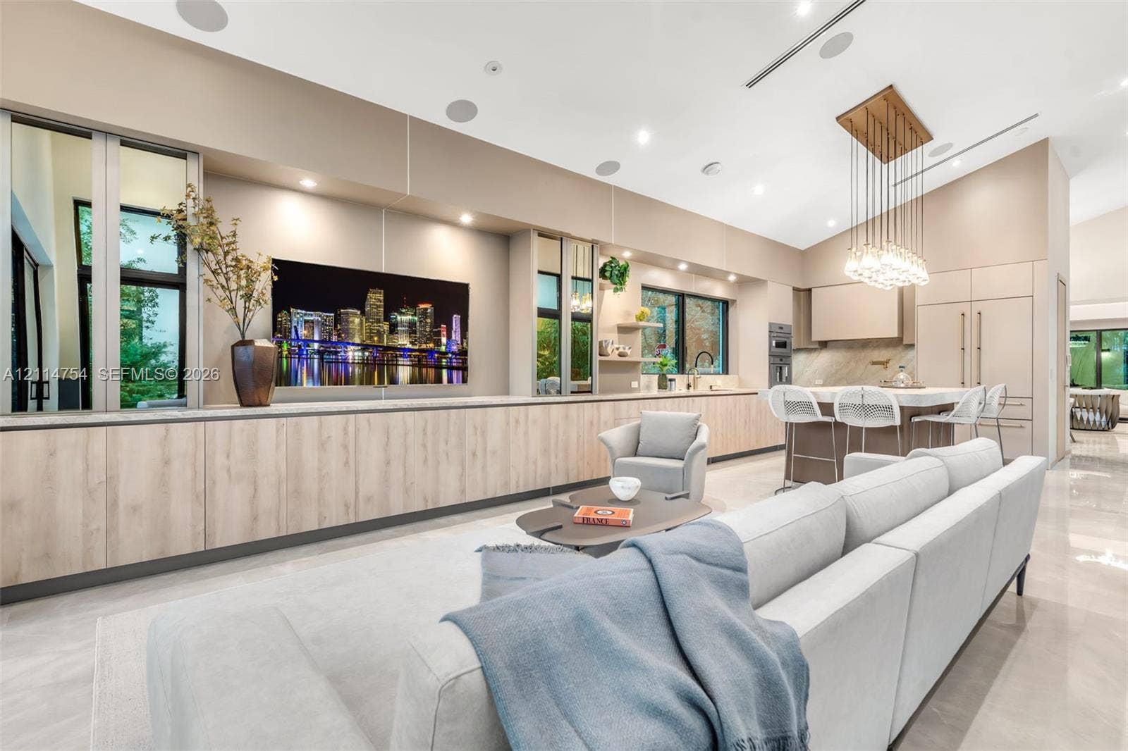 6731 SW 64th Avenue, South Miami, FL 33143 Chefs kitchen featuring a large stone-topped island, floor-to-ceiling glass sliding doors, recessed lighting, multi-bulb pendant lighting, and built-in stainless steel appliances