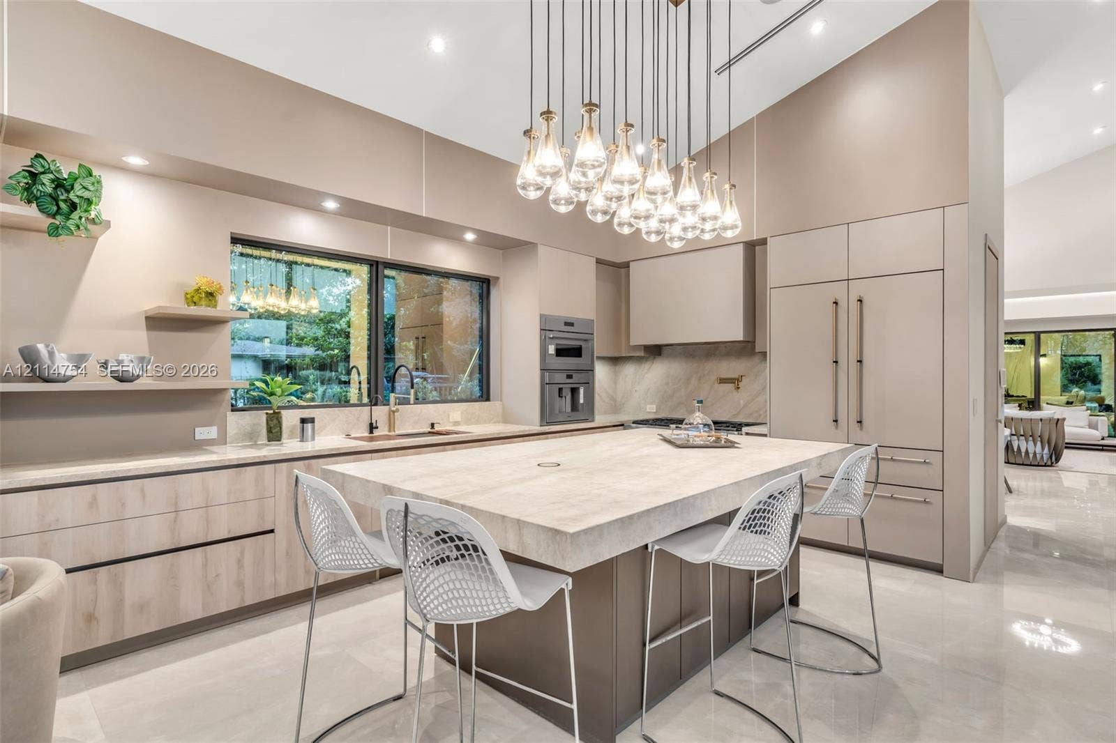 6731 SW 64th Avenue, South Miami, FL 33143 Kitchen featuring flat-panel cabinetry, a large stone-topped central island, built-in stainless steel appliances, and a multi-pendant light fixture beneath a vaulted ceiling