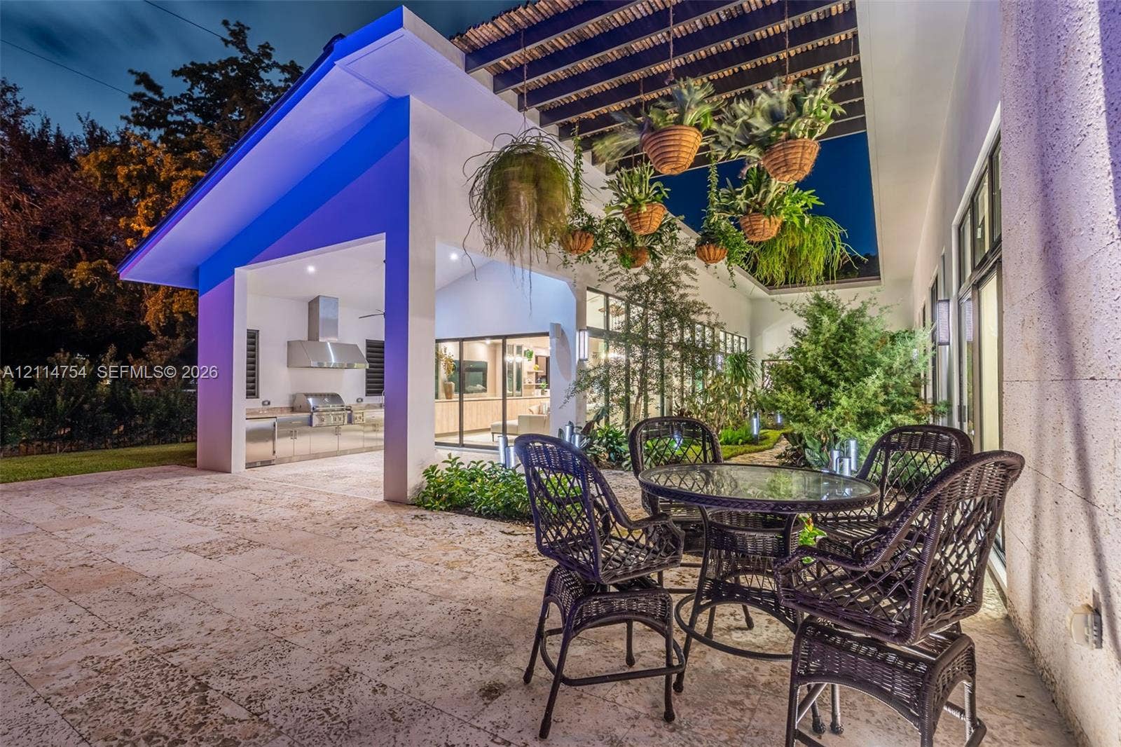 6731 SW 64th Avenue, South Miami, FL 33143 Modern swimming pool featuring stone deck surround, covered outdoor kitchen with stainless steel appliances, and a wood-slat overhead pergola