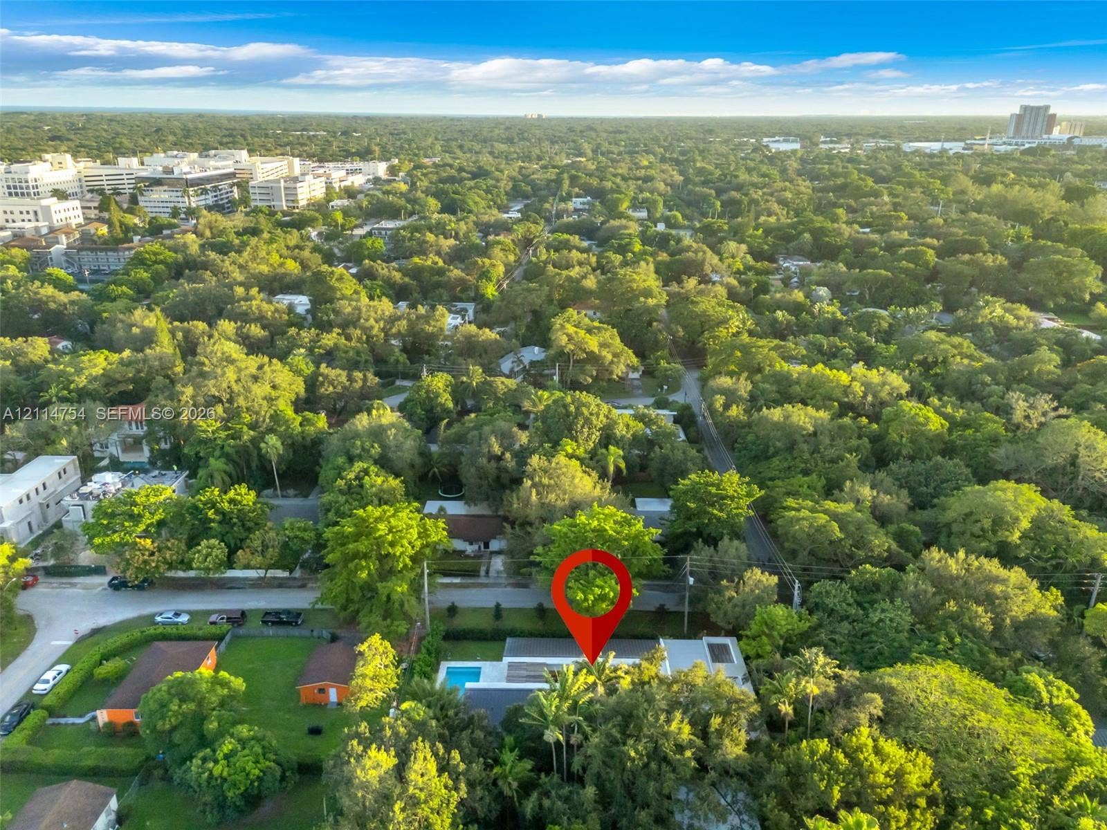 6731 SW 64th Avenue, South Miami, FL 33143 Aerial perspective of a property featuring a private swimming pool, flat roofline, paved patio, and dense mature perimeter landscaping