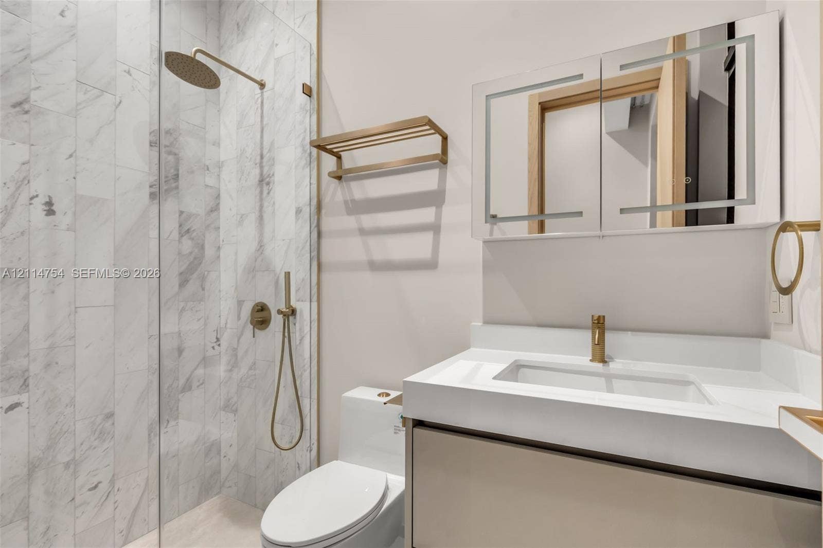 6731 SW 64th Avenue, South Miami, FL 33143 High-ceilinged room featuring large, floor-to-ceiling glass sliding doors, polished stone-finish flooring, recessed ceiling lighting, and a neutral color palette