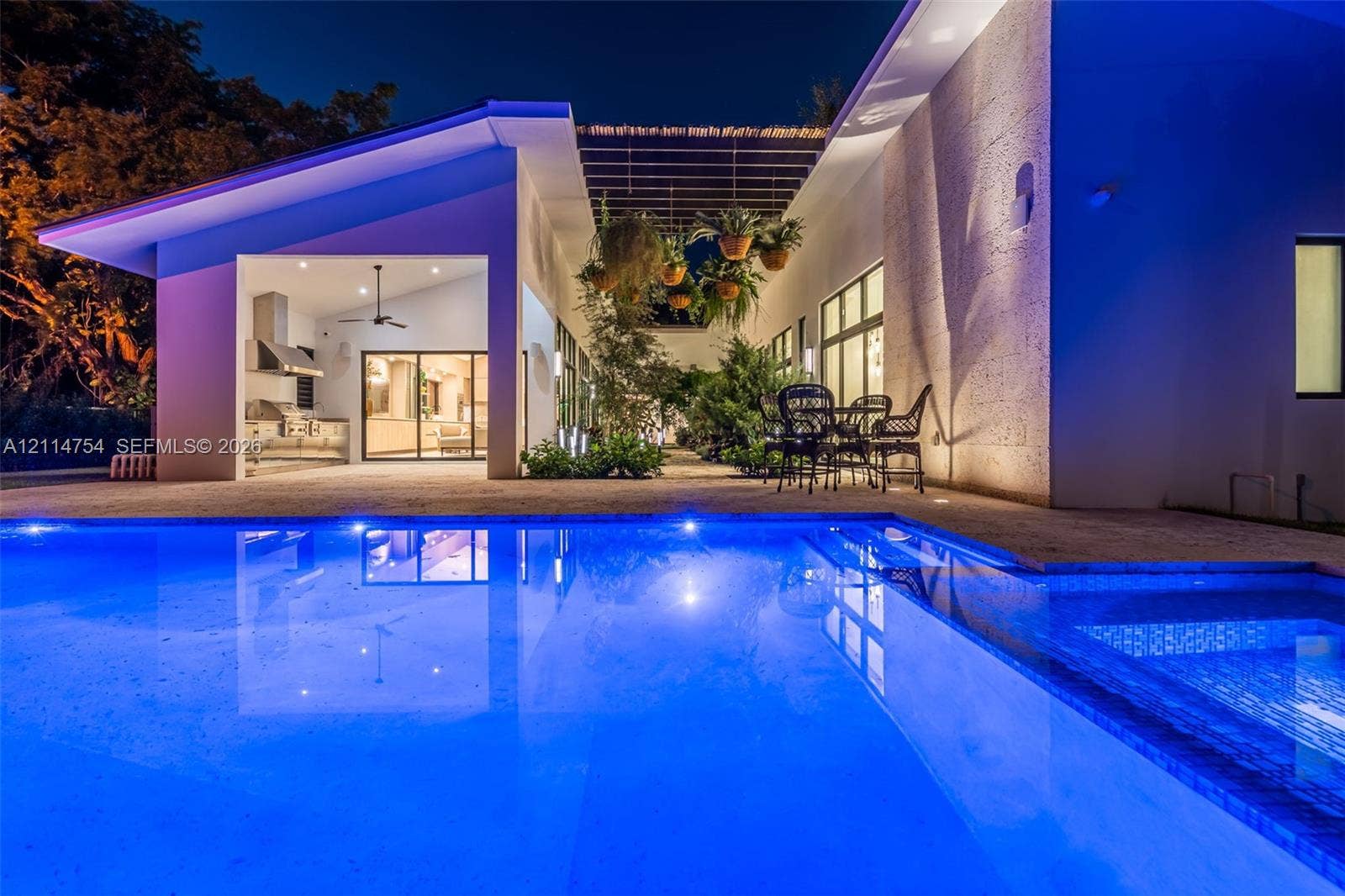 6731 SW 64th Avenue, South Miami, FL 33143 Rectangular in-ground pool with stone-finish decking, covered patio with structural pergola, and expansive glass sliding door panels