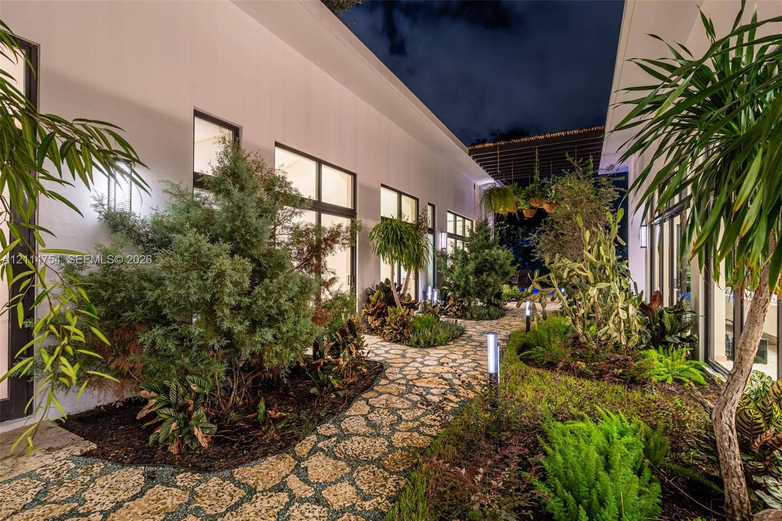 6731 SW 64th Avenue, South Miami, FL 33143 Covered outdoor patio featuring stone flooring, a slatted timber pergola, and a built-in outdoor kitchen with a stainless steel range hood