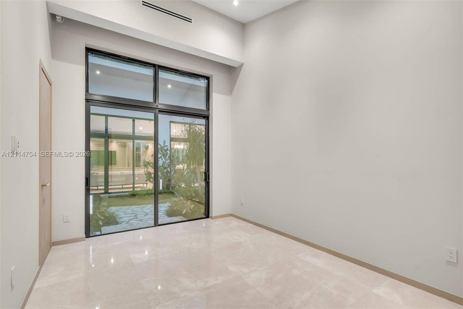 6731 SW 64th Avenue, South Miami, FL 33143 Vaulted ceilings featuring multi-tiered circular and drop-pendant lighting fixtures, floor-to-ceiling glass sliding doors, and light-toned hard-surface flooring