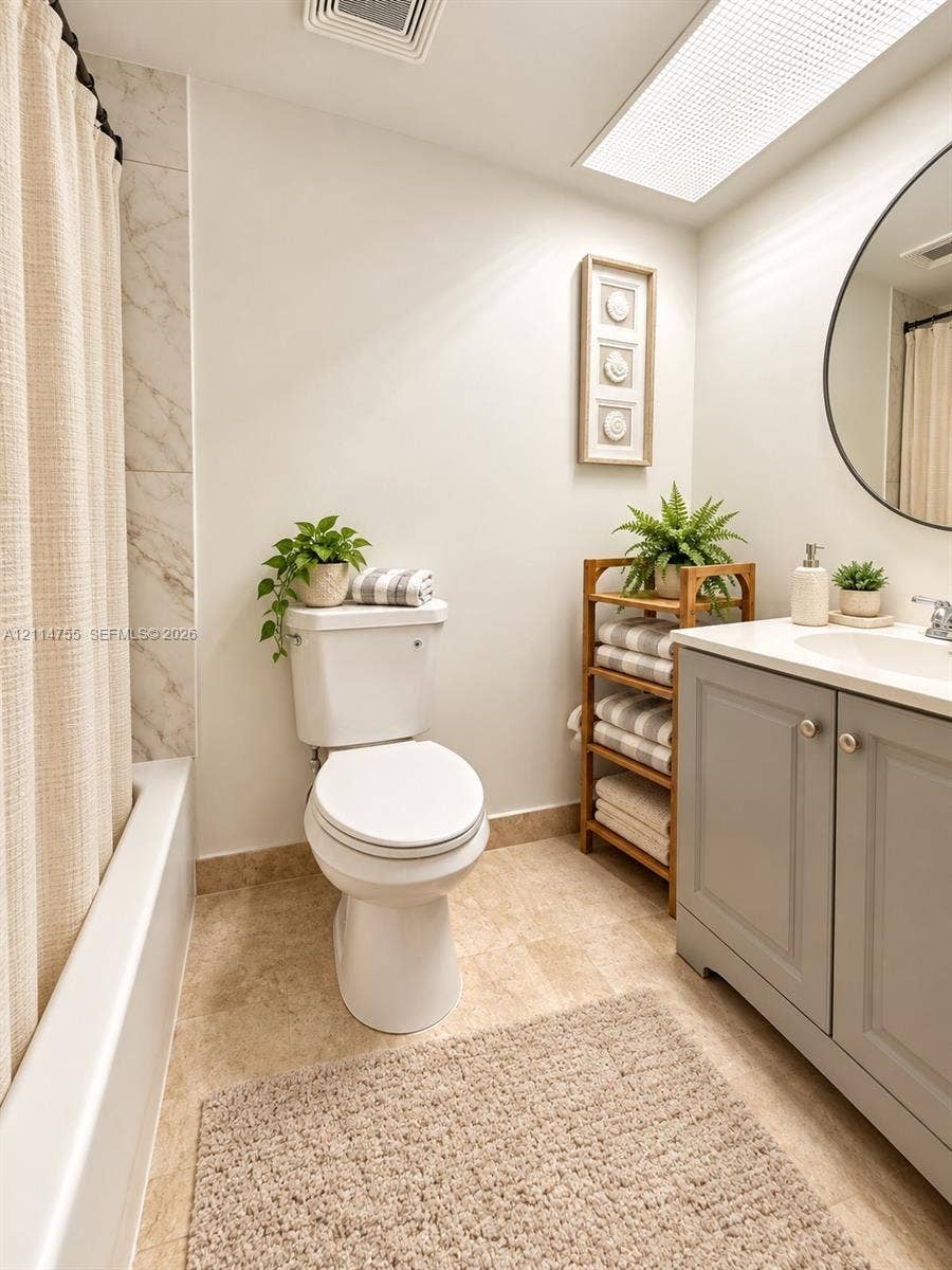 231 174th Street, #MO-3, Sunny Isles Beach, FL 33160 Bathroom featuring a grey vanity with a light-toned countertop, round mirror, recessed ceiling lighting, and a bathtub with tile surround