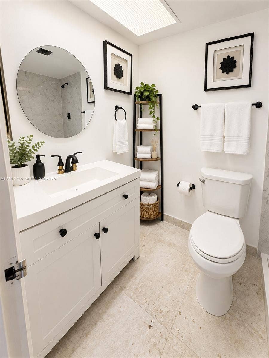 231 174th Street, #MO-3, Sunny Isles Beach, FL 33160 Bathroom featuring a white vanity with an integrated rectangular sink and stone-surface countertop, circular frameless wall mirror, matte black plumbing fixtures, and natural stone flooring