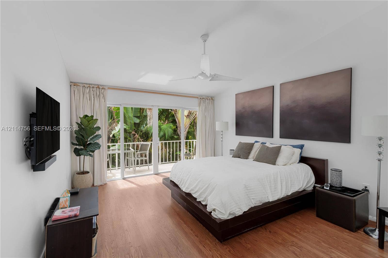 Living space featuring wood-finish flooring, a ceiling fan, and sliding glass doors opening to a balcony