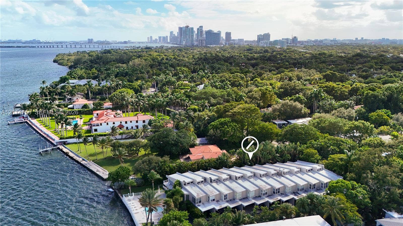 Waterfront property featuring a seawall, expansive lawn, mature landscaping, and proximity to city skyline