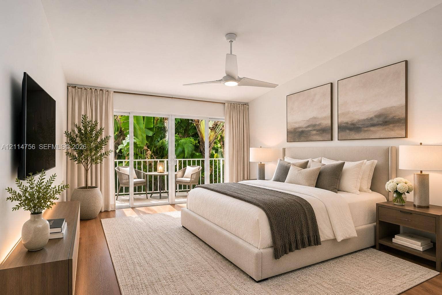 Sliding glass doors opening to a private balcony, wood-finish flooring, and a ceiling fan with integrated lighting