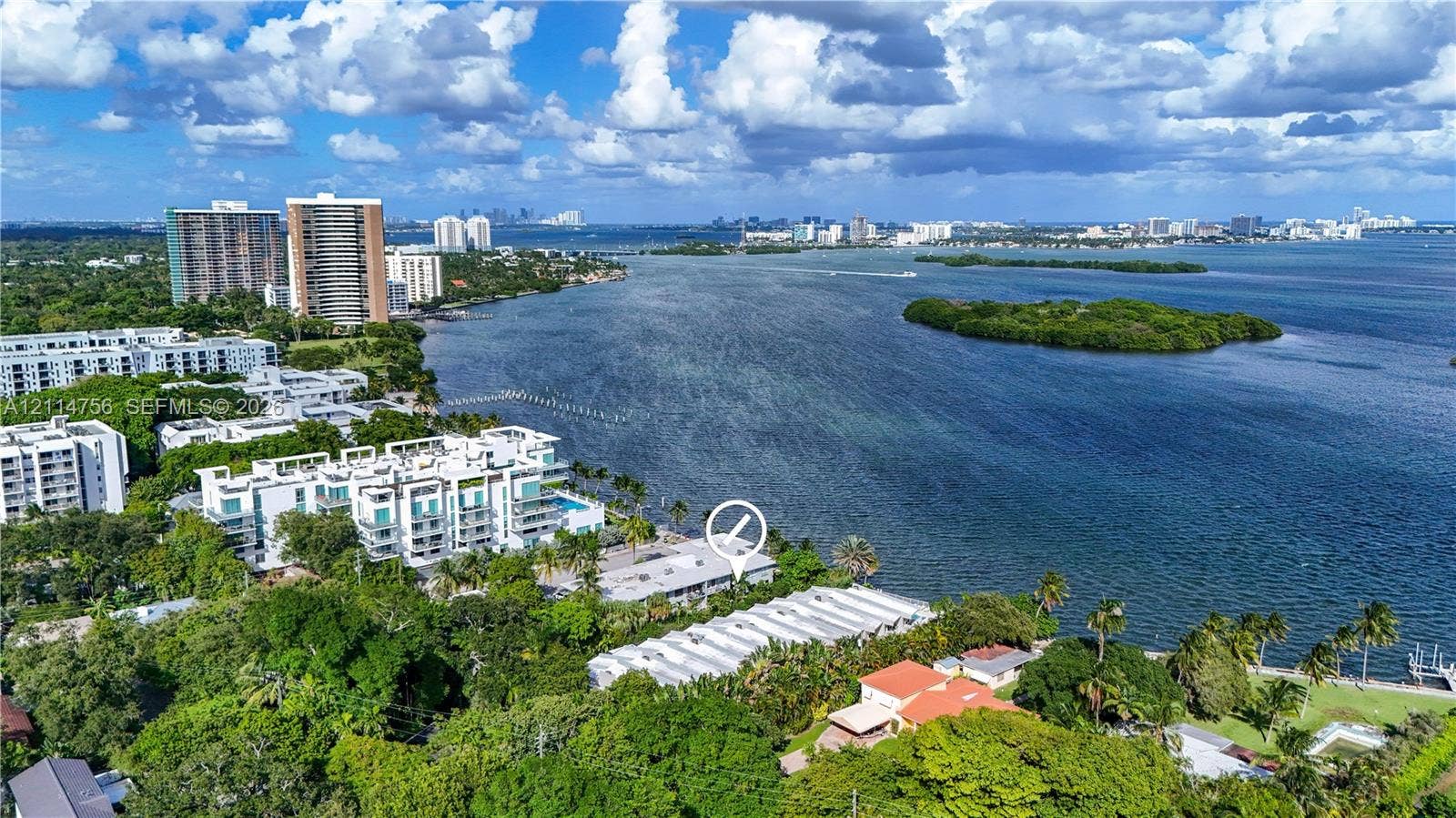 Aerial perspective of a multi-unit property situated on a waterfront parcel, featuring mature trees, dense foliage, and direct proximity to the shoreline