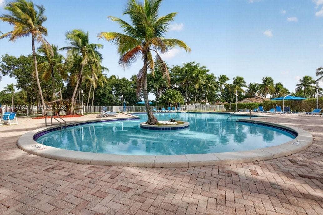 662 NW 170th Terrace, Pembroke Pines, FL 33028 In-ground swimming pool featuring a central island with a palm tree, stone-paver decking, and metal pool safety fencing