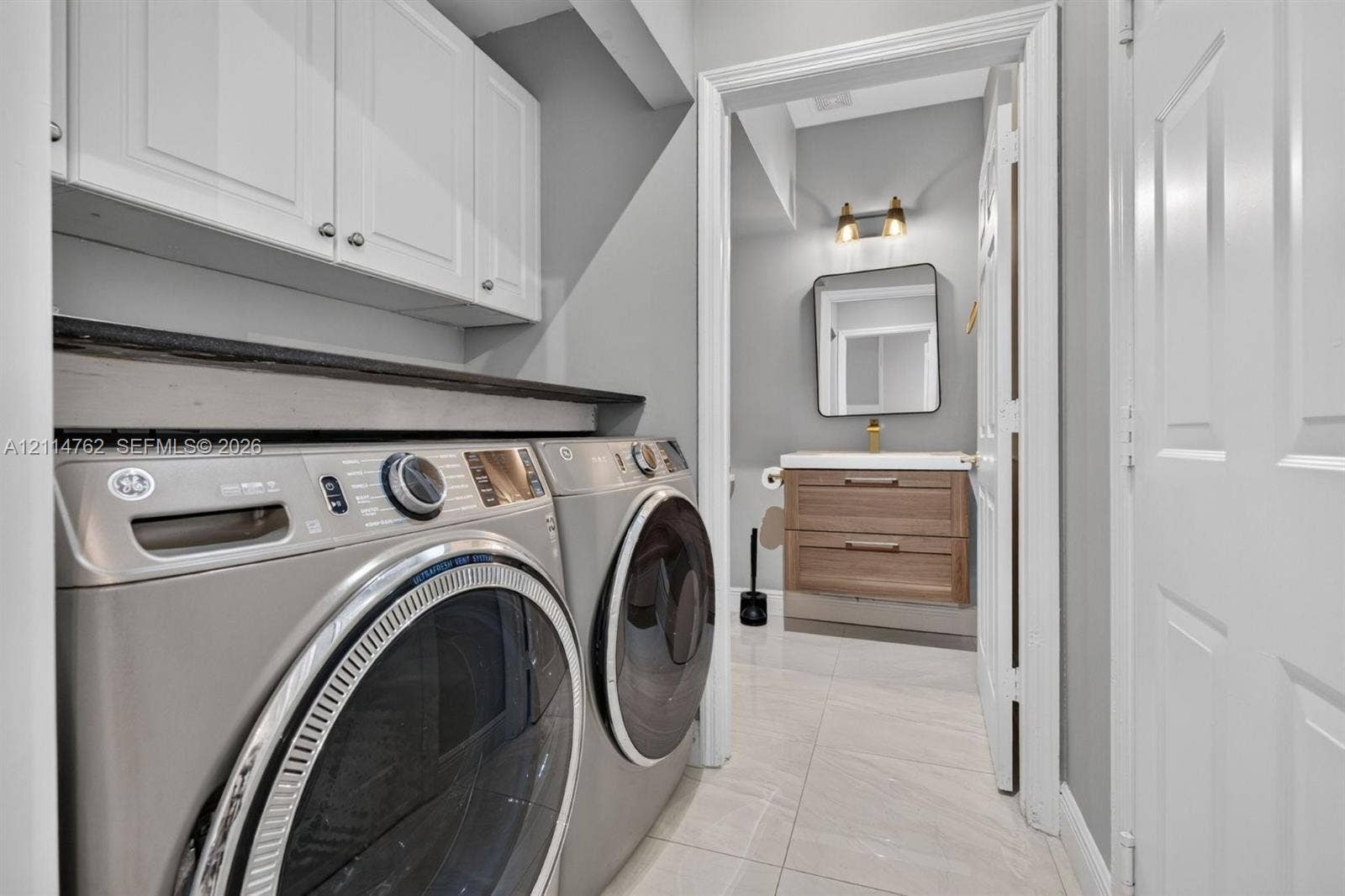 662 NW 170th Terrace, Pembroke Pines, FL 33028 Laundry area featuring white shaker-style wall cabinets and a solid-surface countertop