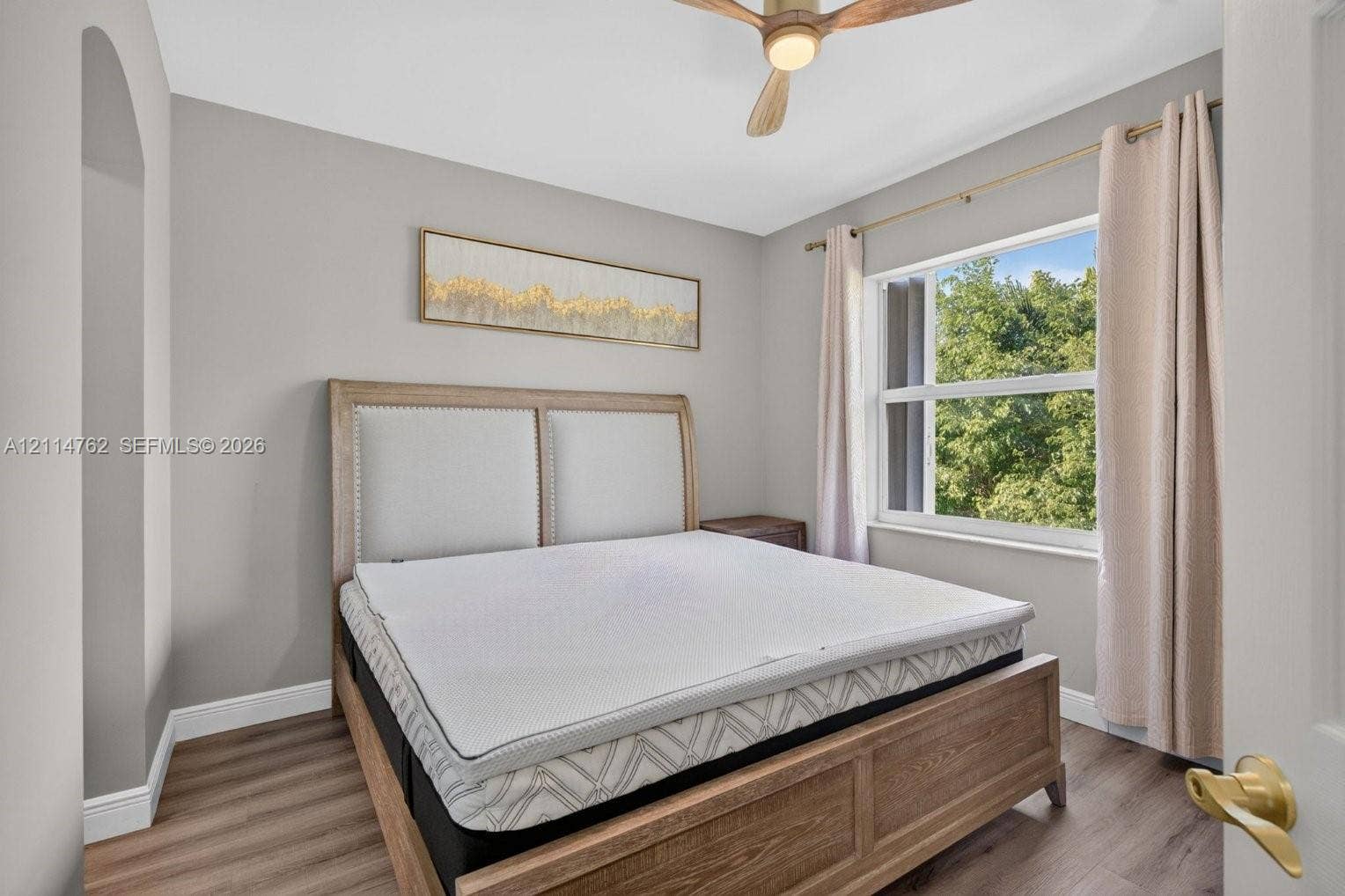 662 NW 170th Terrace, Pembroke Pines, FL 33028 Neutral wall tones with wood-finish flooring, recessed ceiling fan with wood-tone blades, and large window with natural light
