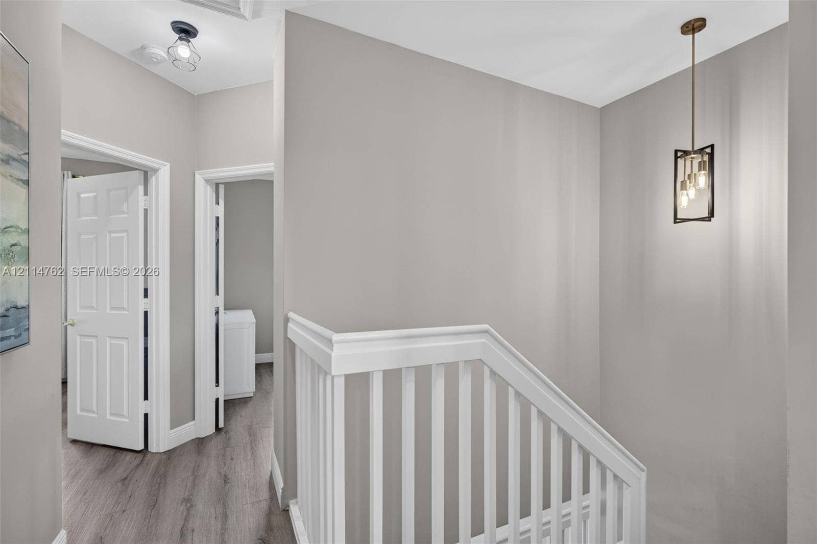 662 NW 170th Terrace, Pembroke Pines, FL 33028 Hallway featuring wood-finish flooring, a white wooden balustrade, and a metal-framed geometric pendant light fixture