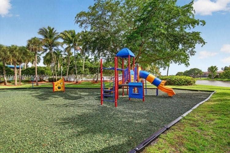 662 NW 170th Terrace, Pembroke Pines, FL 33028 Outdoor recreation area featuring a multi-component play structure, rubberized ground surfacing, mature trees, and landscaping situated alongside a water feature