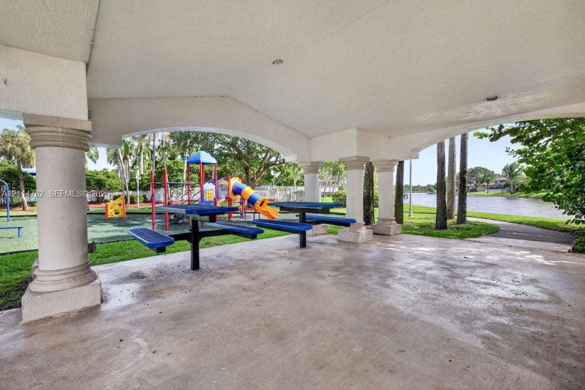 662 NW 170th Terrace, Pembroke Pines, FL 33028 Covered pavilion with architectural columns, concrete flooring, and recreational space featuring playground equipment and paved walking paths