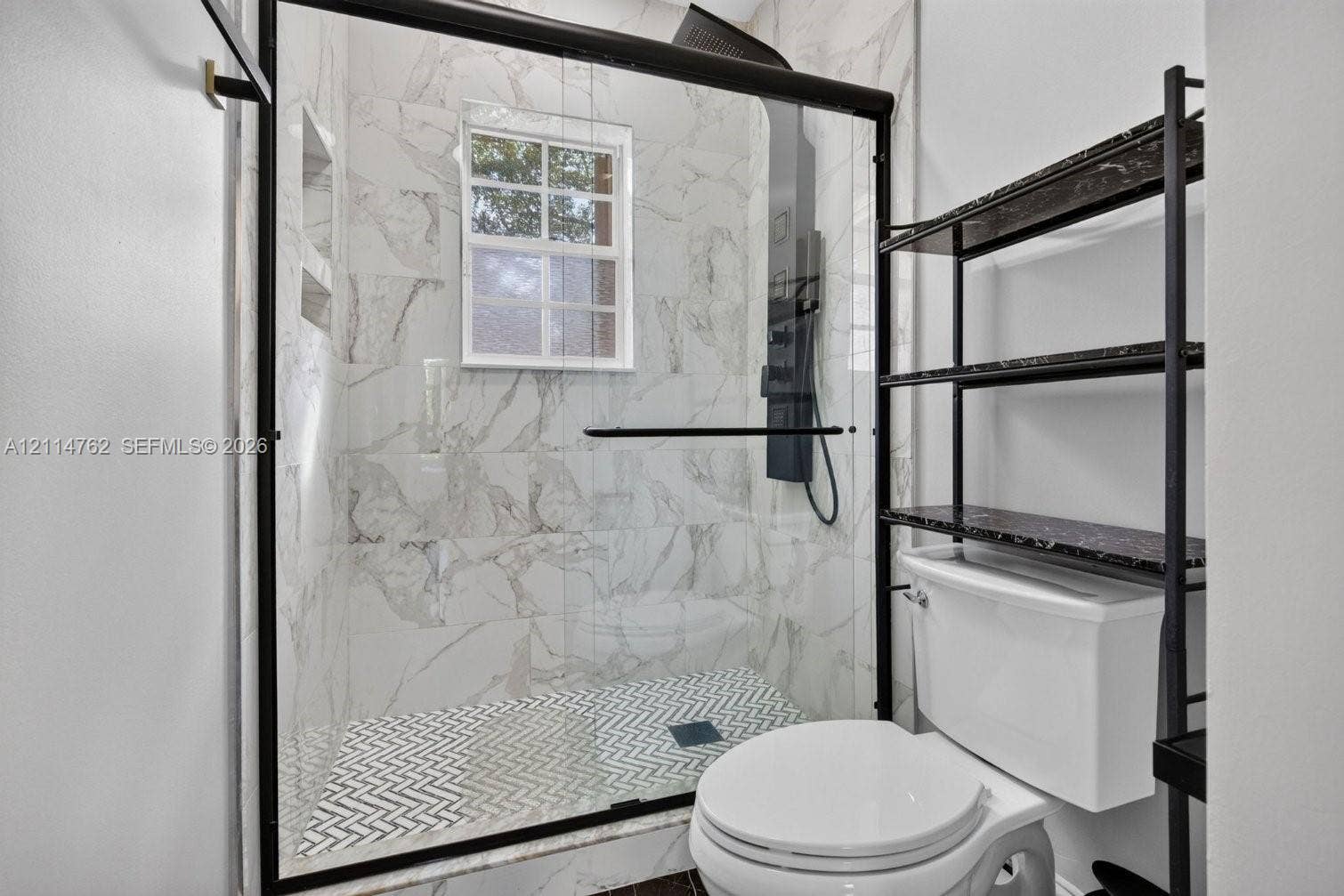662 NW 170th Terrace, Pembroke Pines, FL 33028 Walk-in shower featuring floor-to-ceiling stone-look tile, herringbone patterned tile flooring, a black-framed glass enclosure, and a built-in recessed wall niche