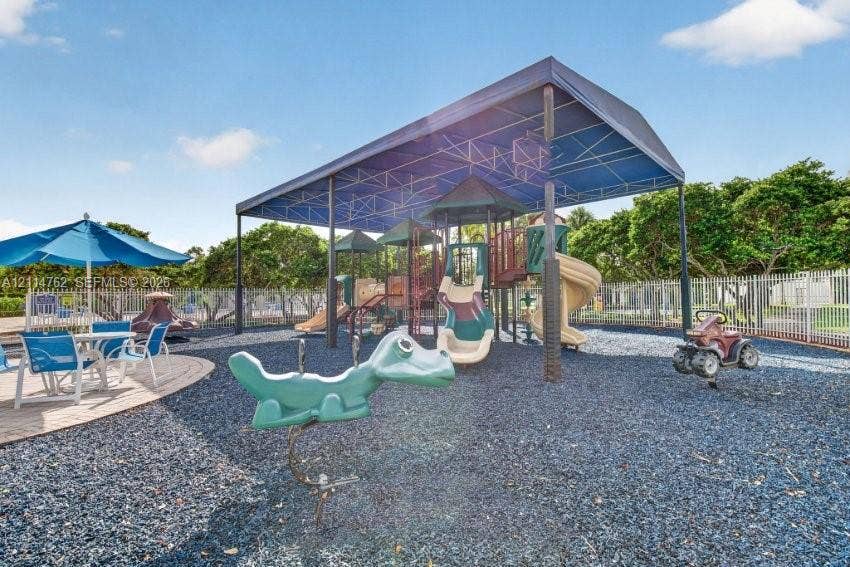 662 NW 170th Terrace, Pembroke Pines, FL 33028 Recreational area featuring a covered playground structure with slides, integrated rocker equipment, and a perimeter metal fence