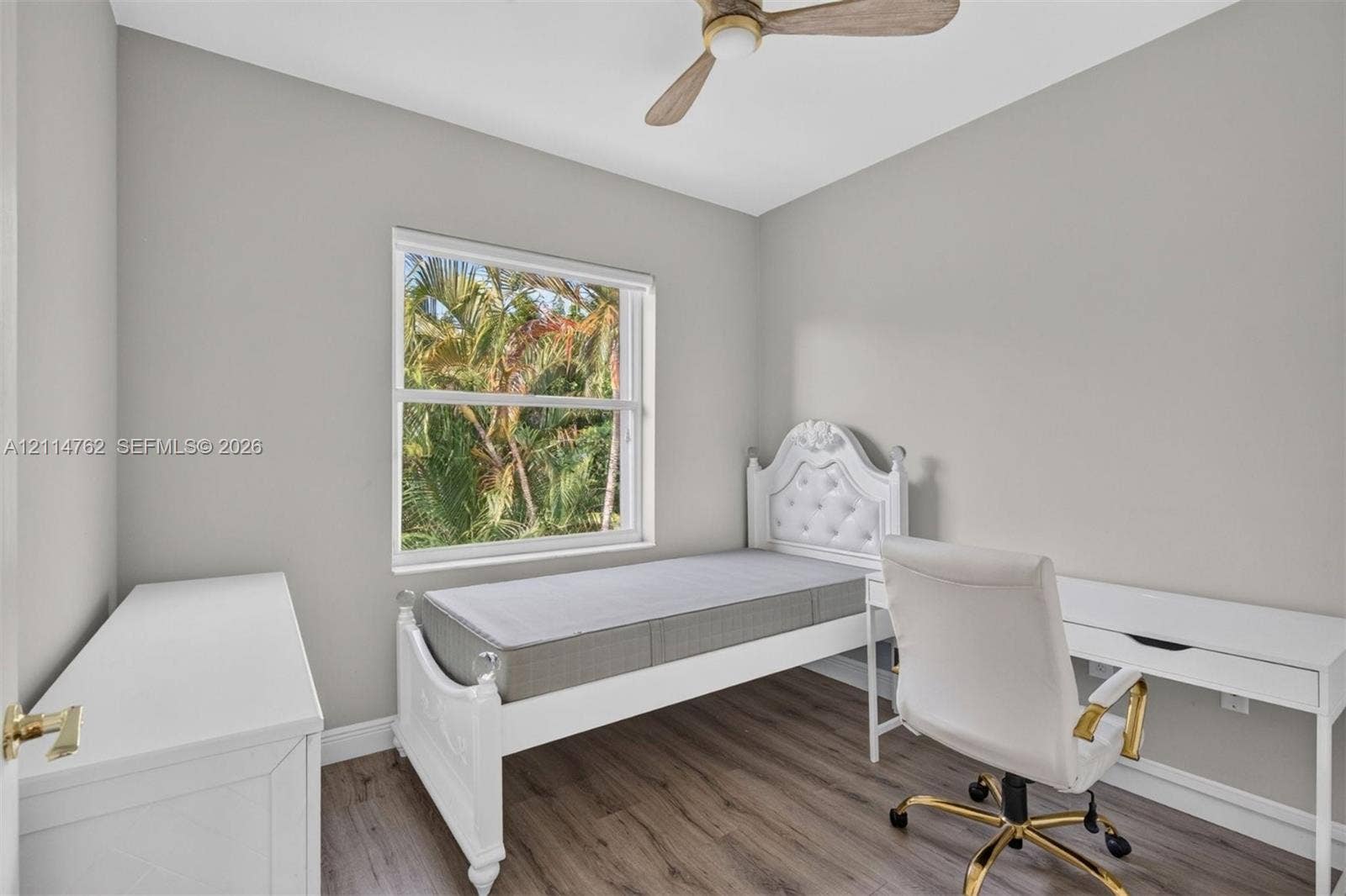 662 NW 170th Terrace, Pembroke Pines, FL 33028 Neutral-toned interior space featuring wood-finish flooring, a ceiling fan with light fixture, and a large window providing natural light and exterior foliage