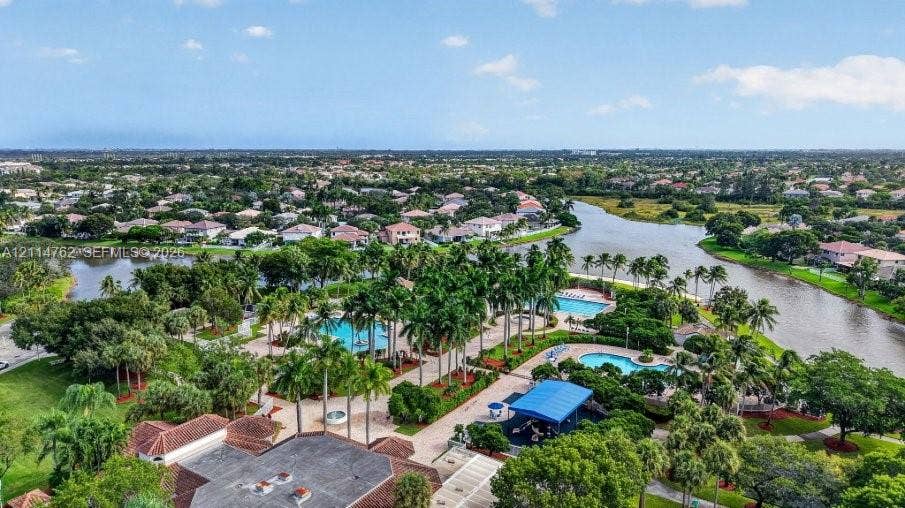 662 NW 170th Terrace, Pembroke Pines, FL 33028 Community complex featuring multiple swimming pools, paved walkways, palm tree landscaping, and direct water frontage