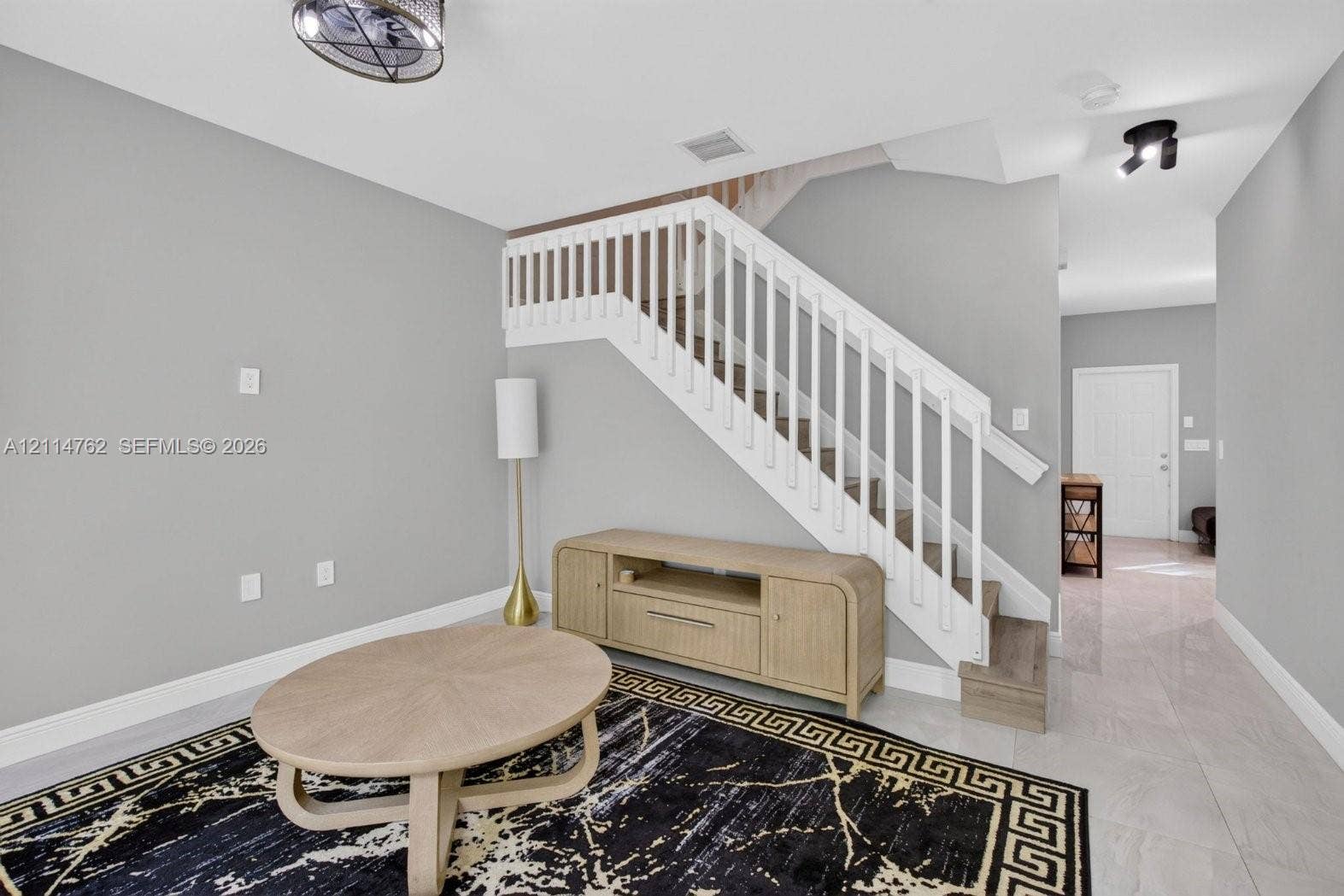 662 NW 170th Terrace, Pembroke Pines, FL 33028 Staircase featuring white balusters and wood-finish treads, complemented by neutral wall paint and polished tile flooring throughout