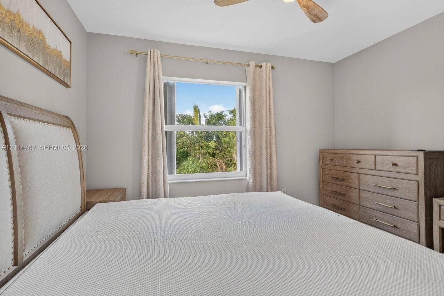 662 NW 170th Terrace, Pembroke Pines, FL 33028 Neutral wall palette featuring a centered window with metallic rod hardware and a ceiling-mounted fan with wood-finish blades