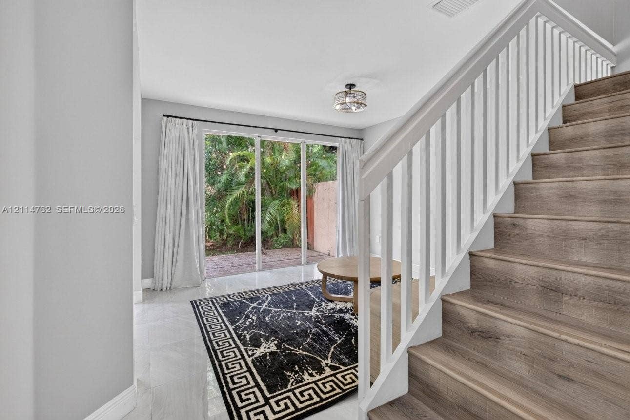 662 NW 170th Terrace, Pembroke Pines, FL 33028 Interior featuring wood-finish staircase treads with white balusters, polished tile flooring, and glass sliding doors