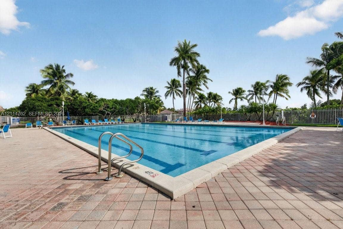 662 NW 170th Terrace, Pembroke Pines, FL 33028 Large swimming pool featuring multi-lane lap markers, stainless steel handrails, and a surrounding paver patio lined with mature palm trees