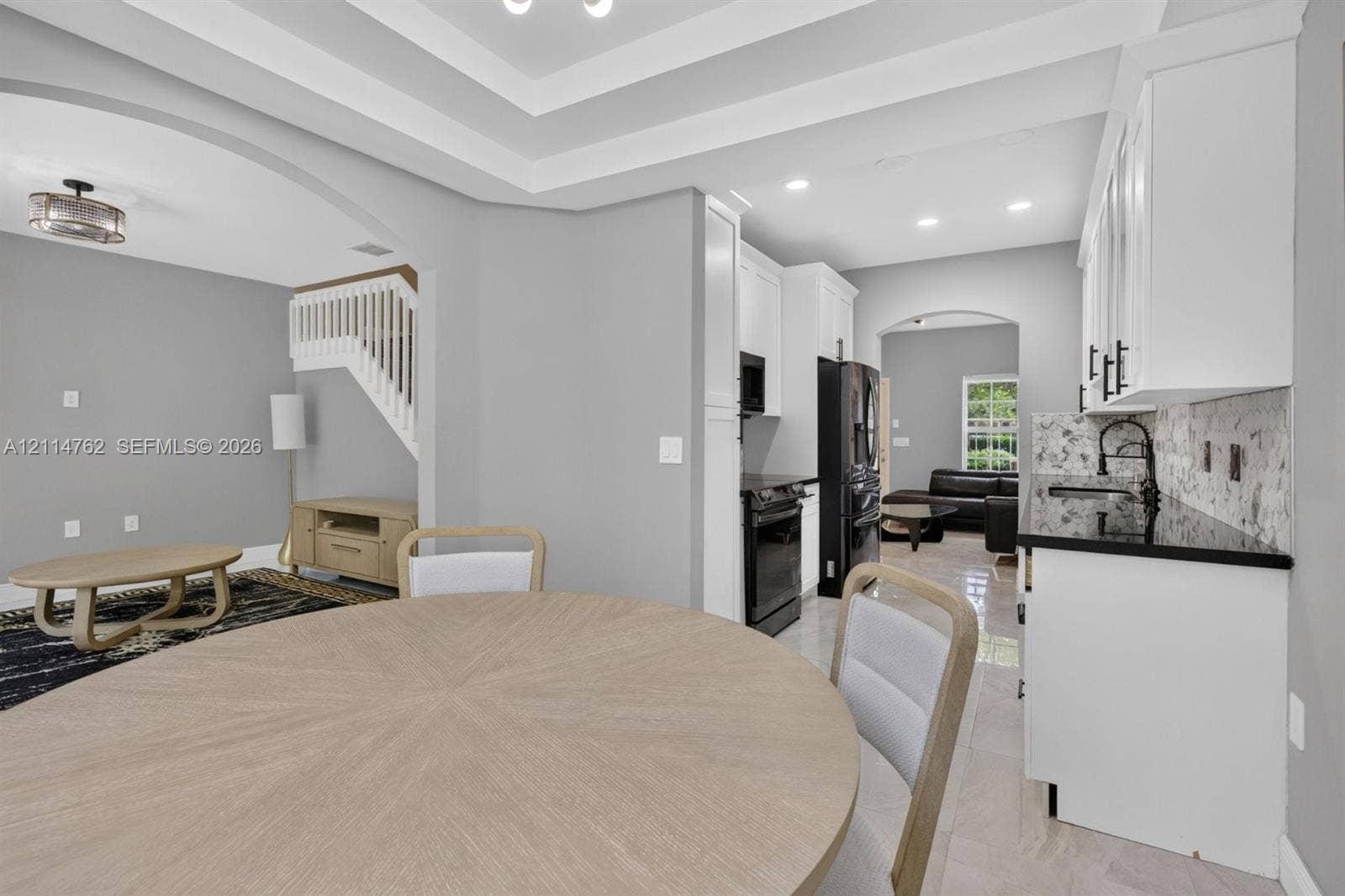 662 NW 170th Terrace, Pembroke Pines, FL 33028 Kitchen featuring white cabinetry, black stone countertops, matte black hardware, recessed lighting, and tray ceilings