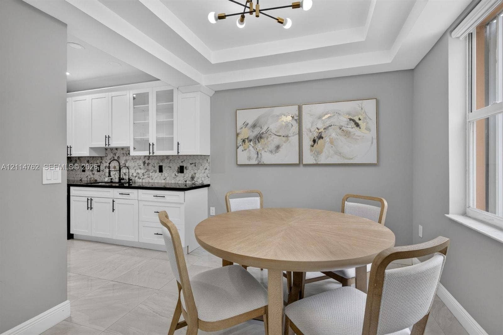 662 NW 170th Terrace, Pembroke Pines, FL 33028 Tray ceiling with integrated lighting, white shaker cabinetry with glass-front uppers, dark stone countertops, patterned tile backsplash, and large-format tile flooring