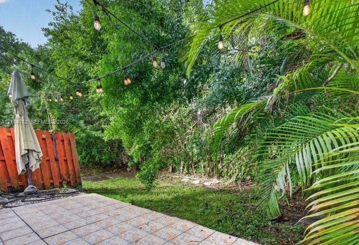 662 NW 170th Terrace, Pembroke Pines, FL 33028 Outdoor patio featuring tiled flooring, a vertical wood fence, and string lighting