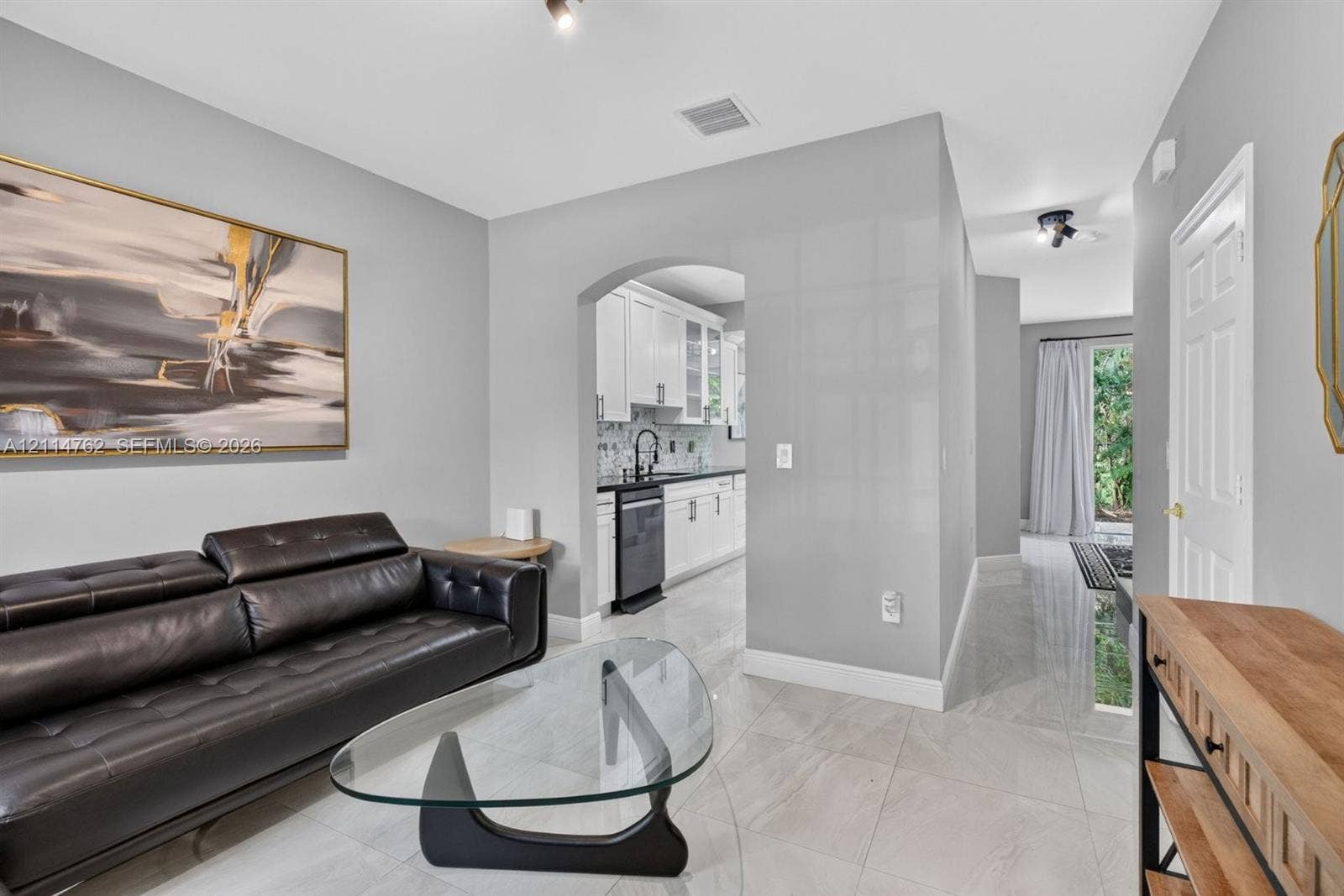 662 NW 170th Terrace, Pembroke Pines, FL 33028 Interior featuring polished stone-look tile flooring, arched entryway, and white kitchen cabinetry with high-contrast dark countertops