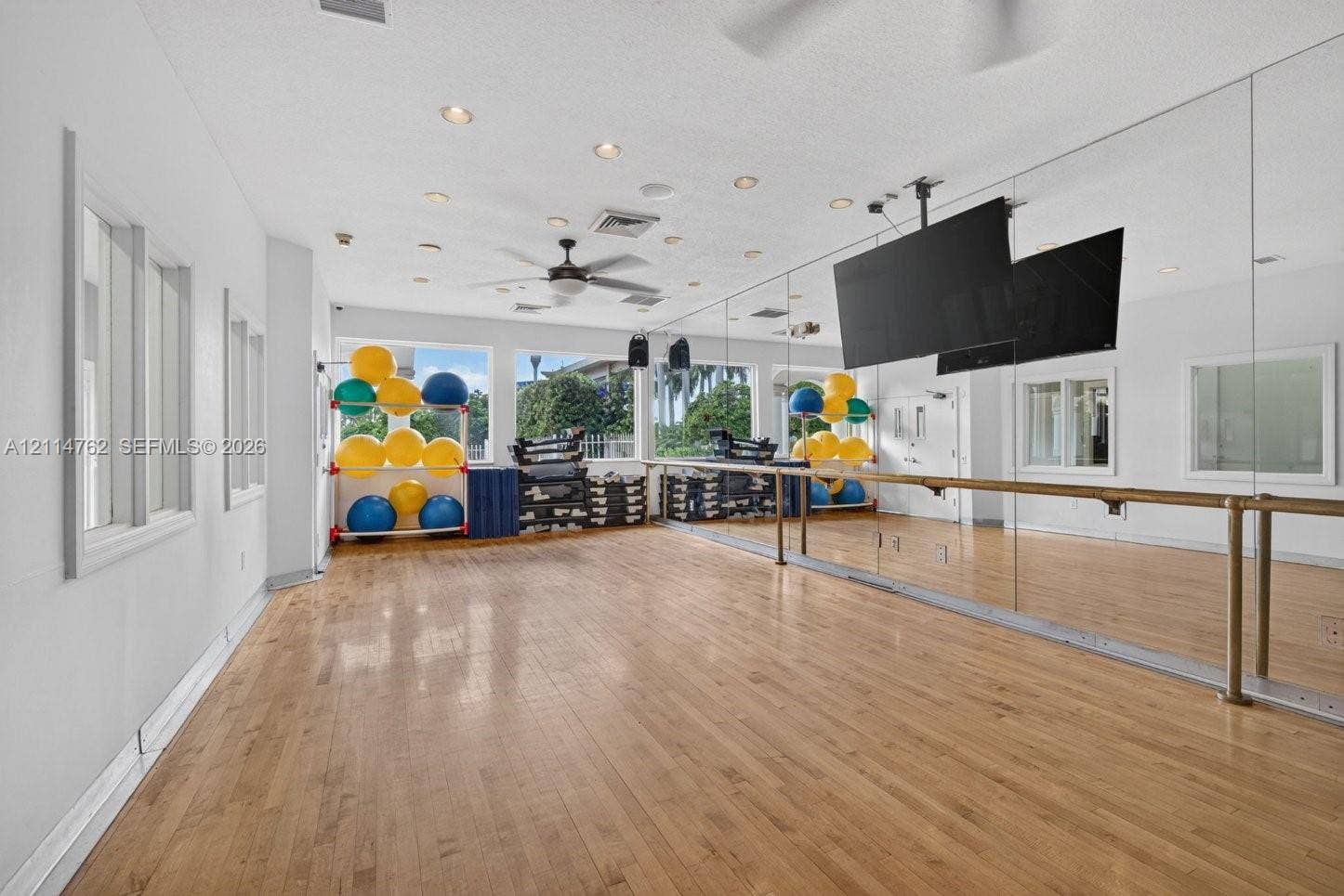 662 NW 170th Terrace, Pembroke Pines, FL 33028 Spacious room featuring wood-finish flooring, full-length wall mirrors, a mounted ballet barre, recessed lighting, and a ceiling fan